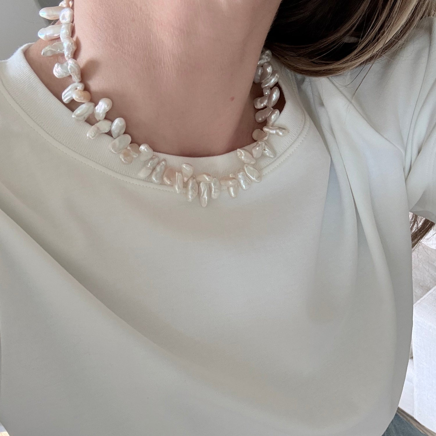 Close-up of a person wearing a white dress with pearl details.