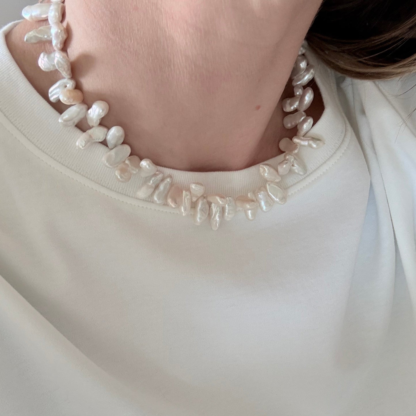 Close-up of a person wearing a white dress with a beaded neckline.
