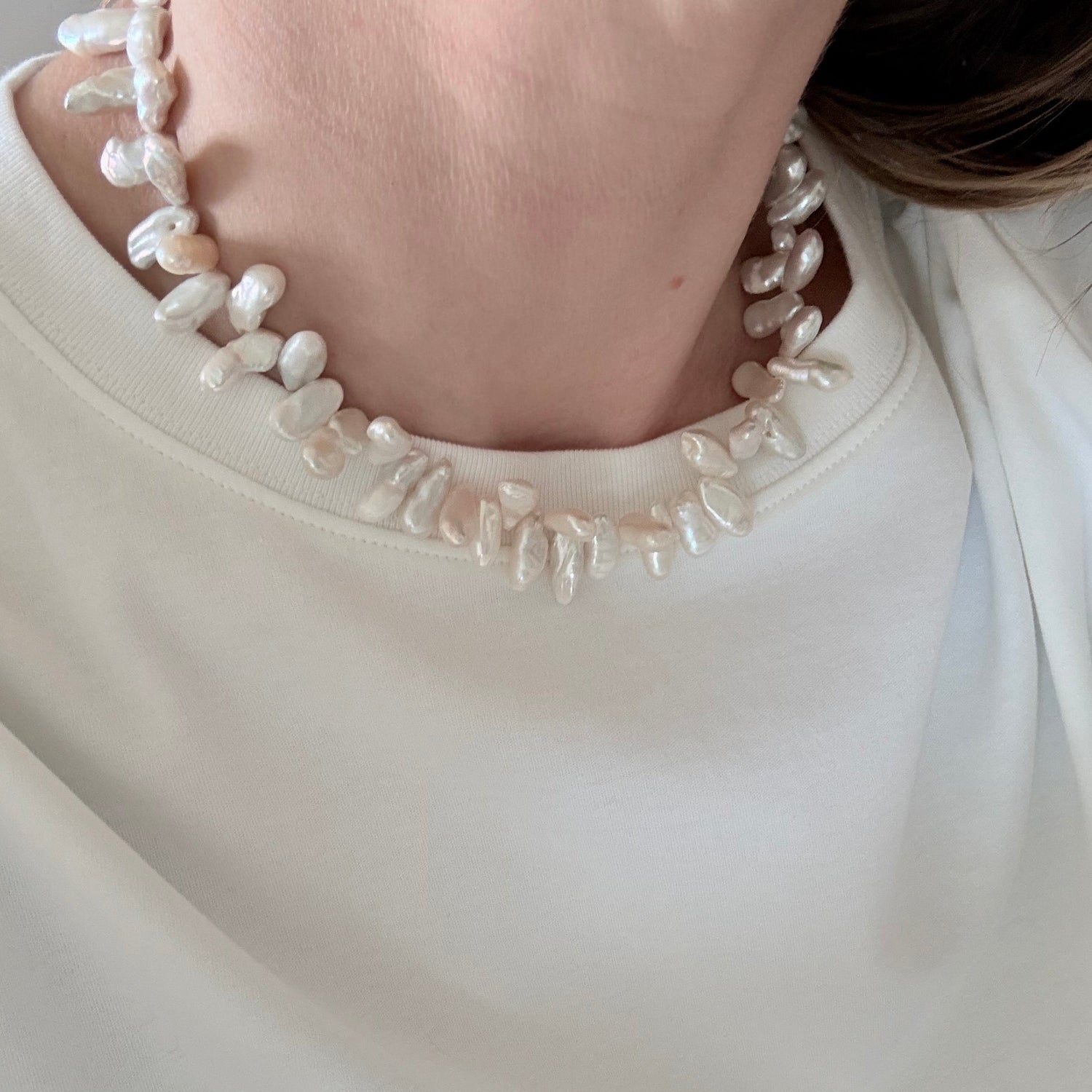 Close-up of a person wearing a white dress with a beaded neckline.