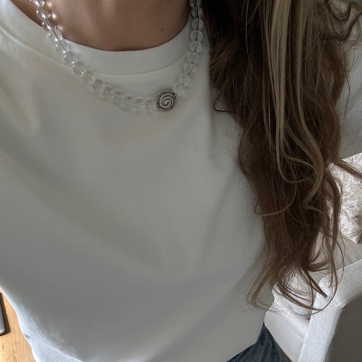 Person wearing a white sleeveless top with decorative details and blue jeans.