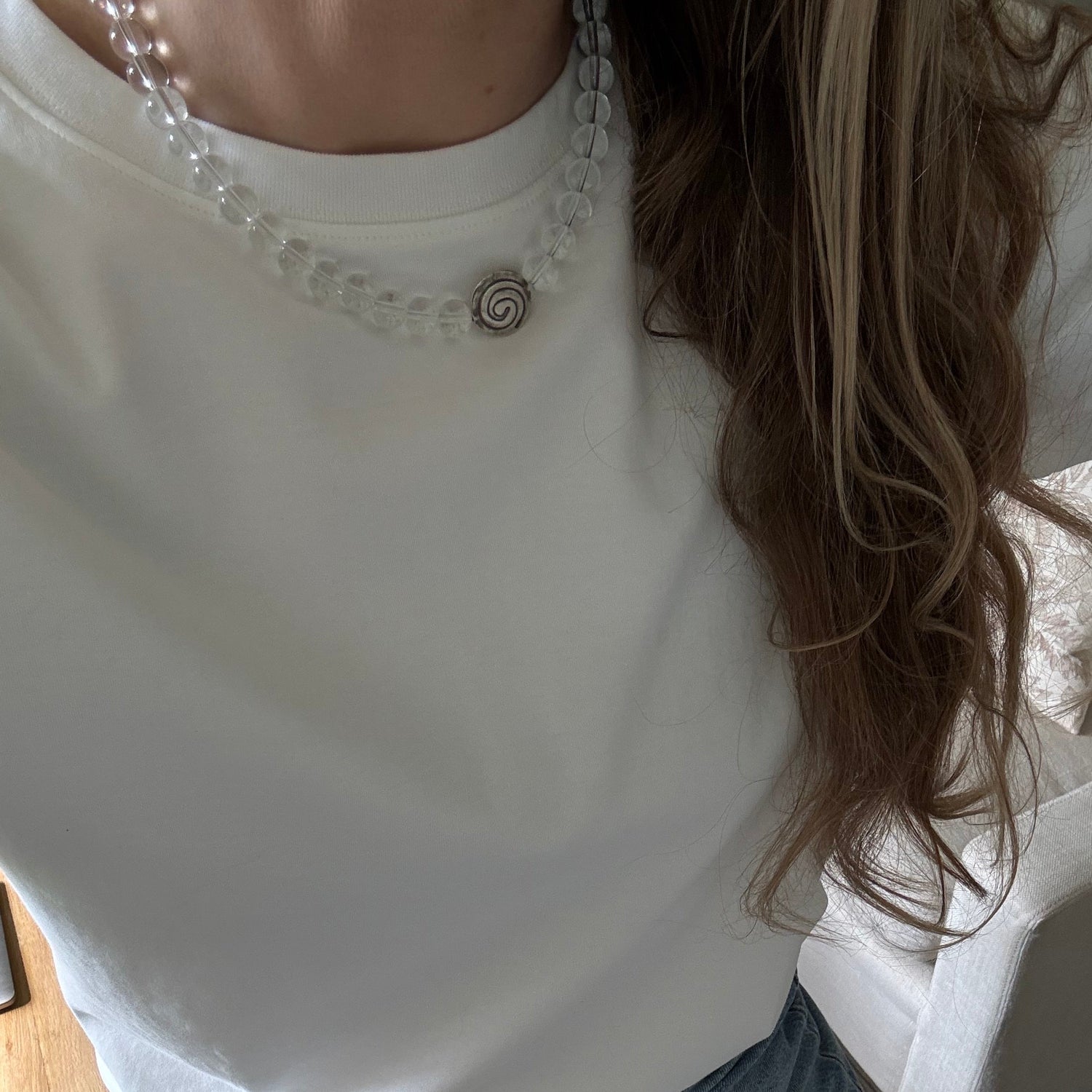 Person wearing a white sleeveless top with decorative details and blue jeans.