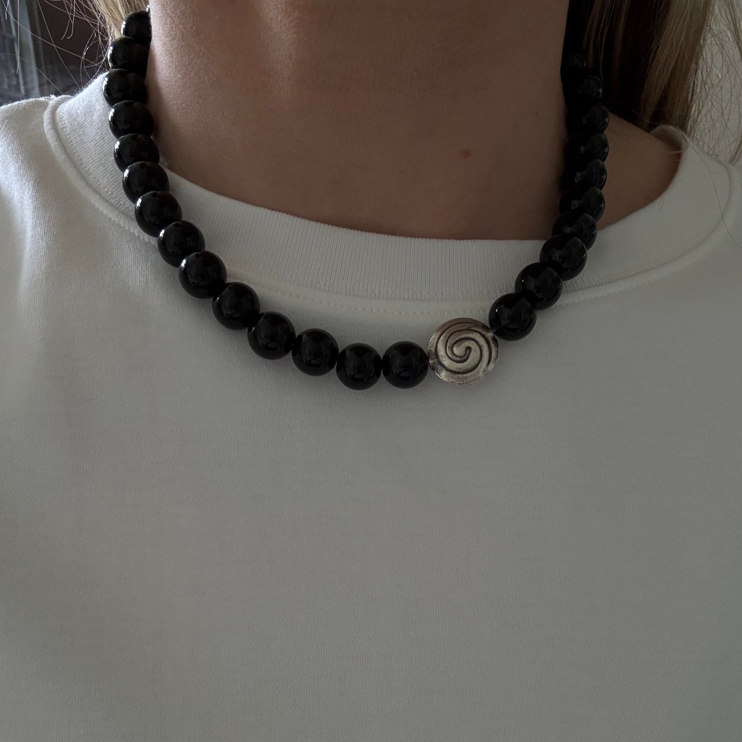 Black beaded bracelet with a spiral charm on a white background