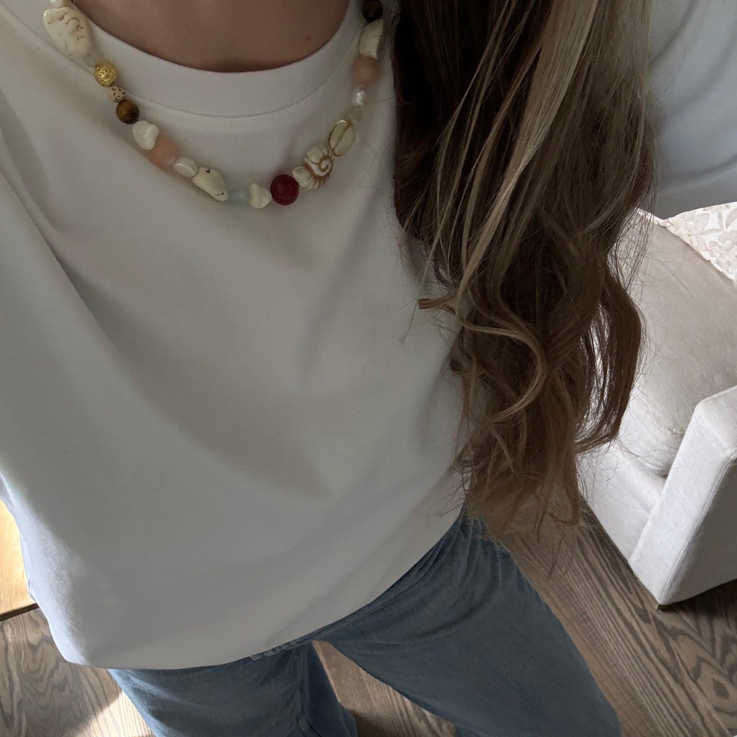 Person wearing a white top and blue jeans on a wooden floor.
