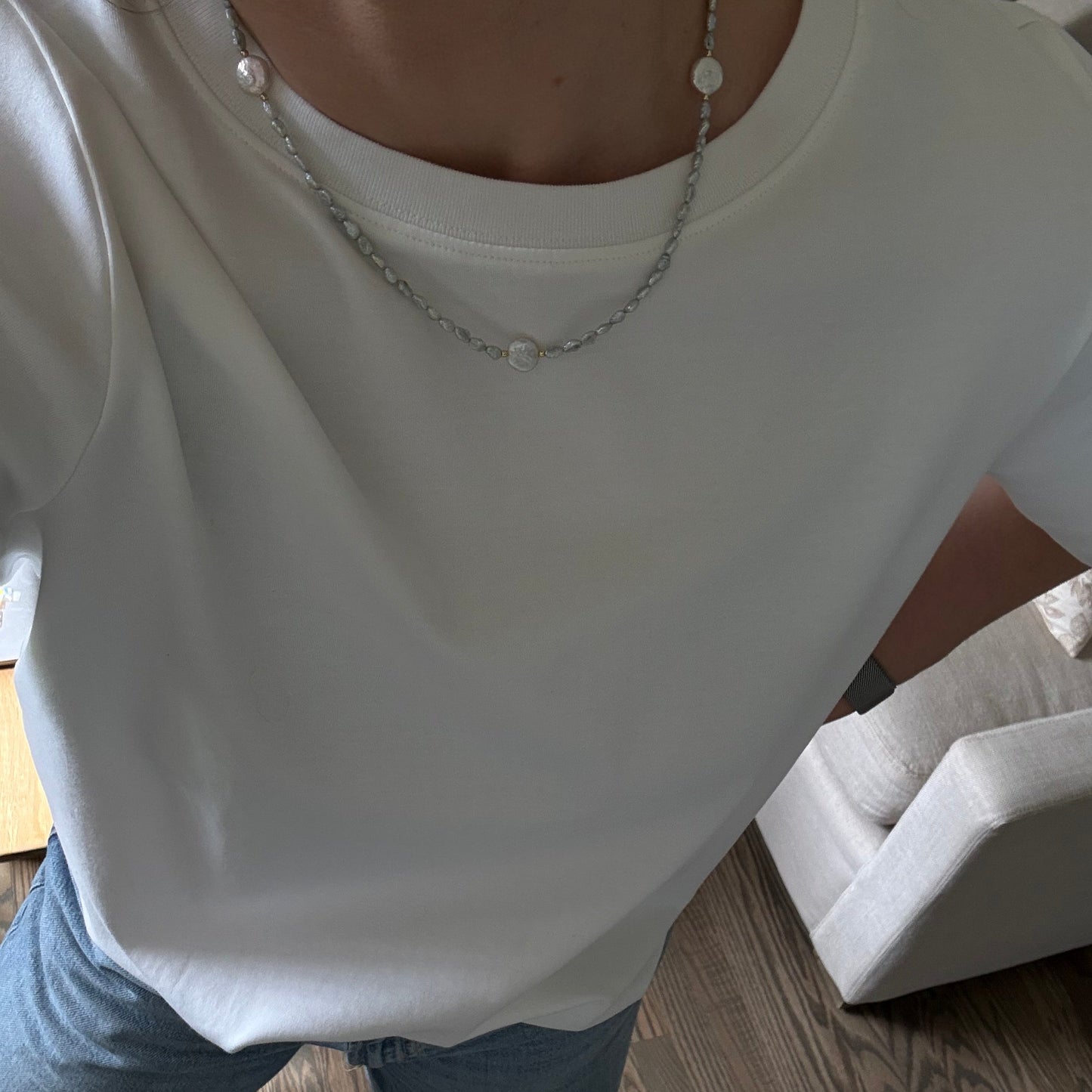 Person wearing a white sleeveless top and blue jeans on a wooden floor.