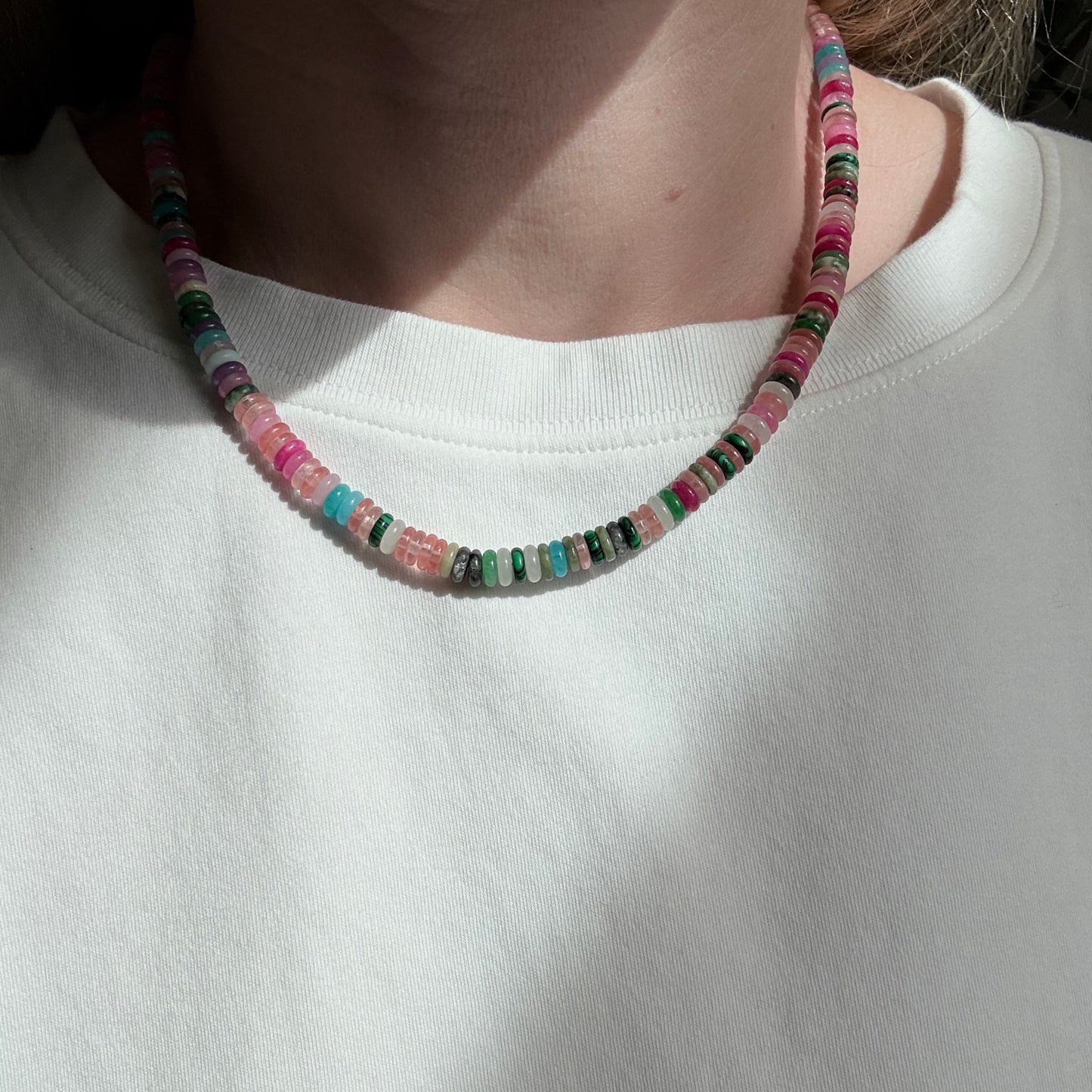Multicolored beaded bracelet on a person's wrist against a white background