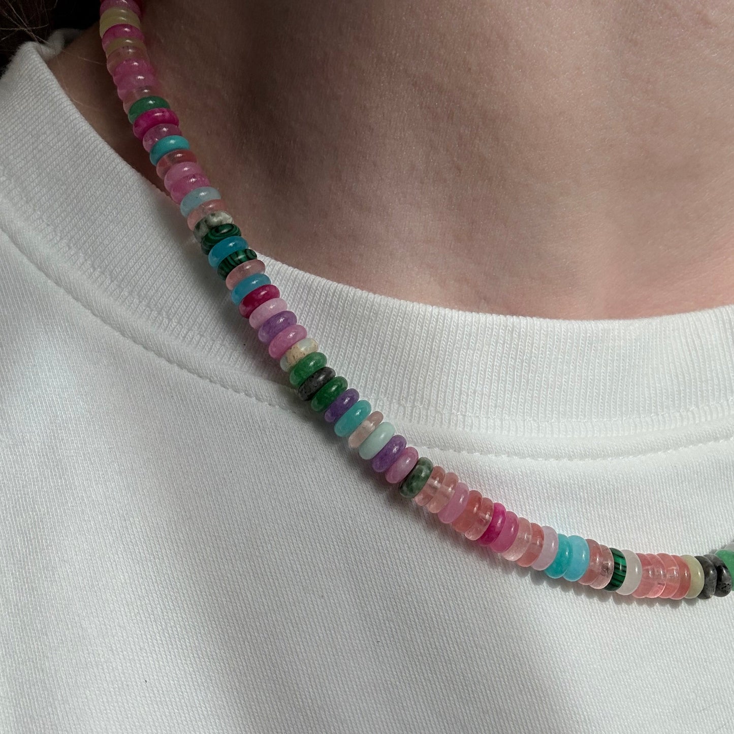 Multicolored beaded necklace on a person's neck against a white background