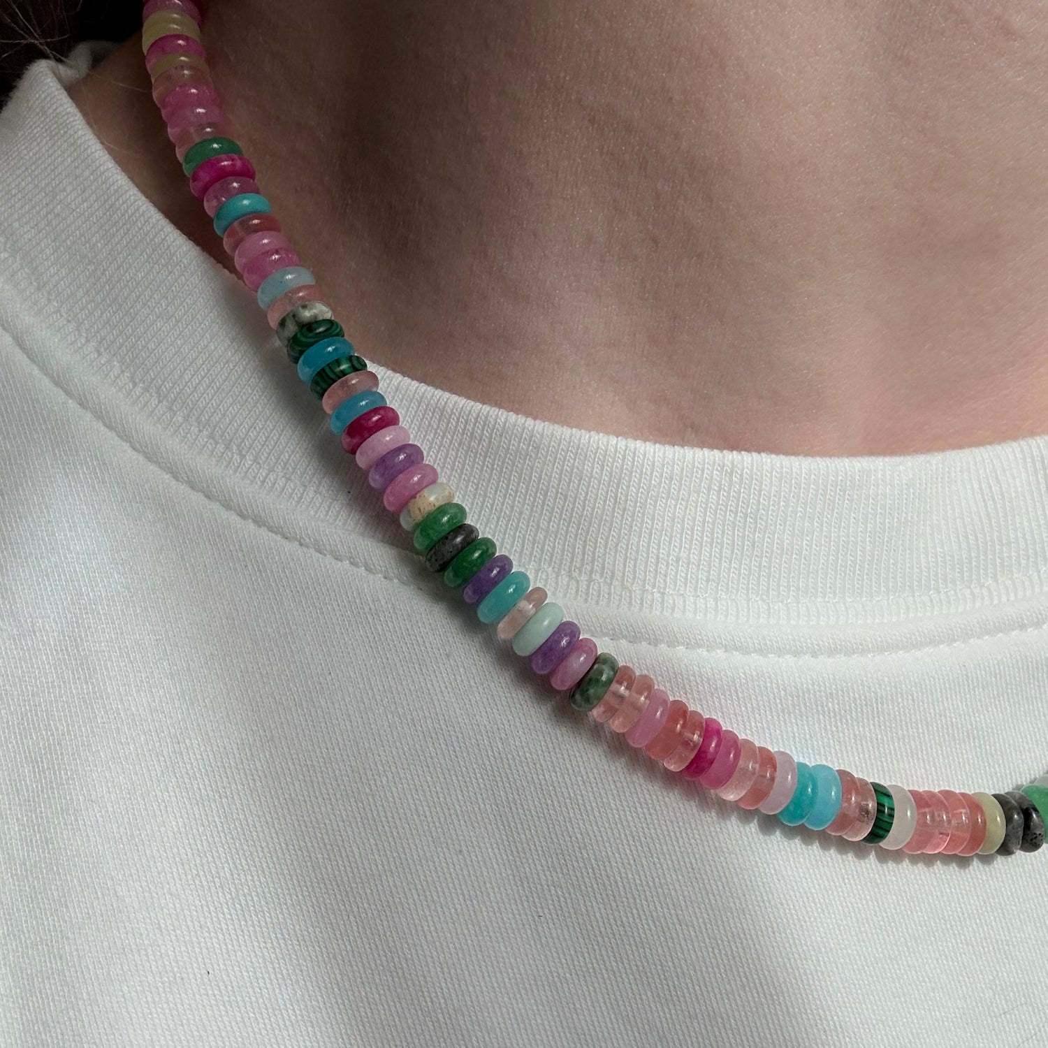 Multicolored beaded necklace on a person's neck against a white background
