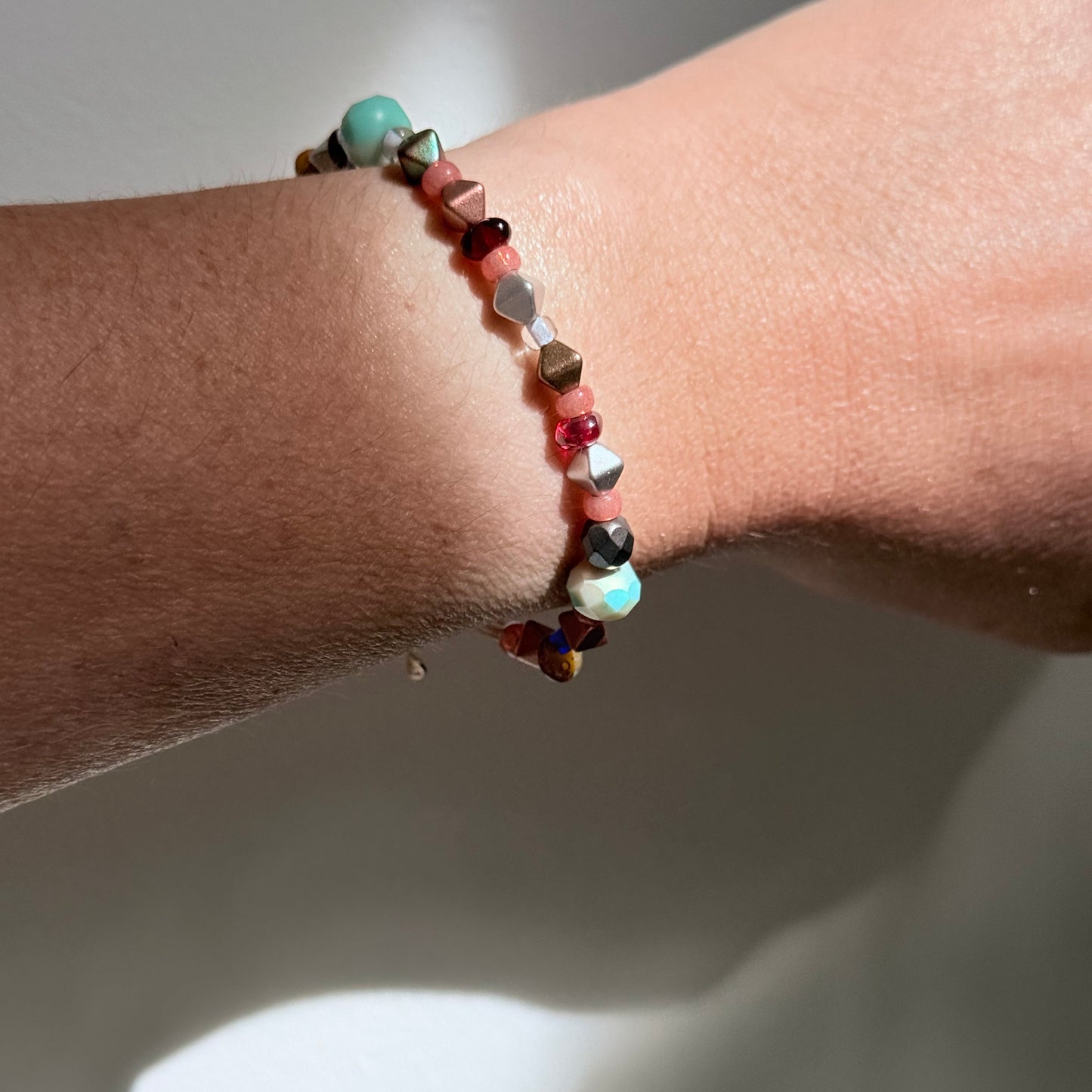 Close-up of a wrist wearing a beaded bracelet with a neutral background