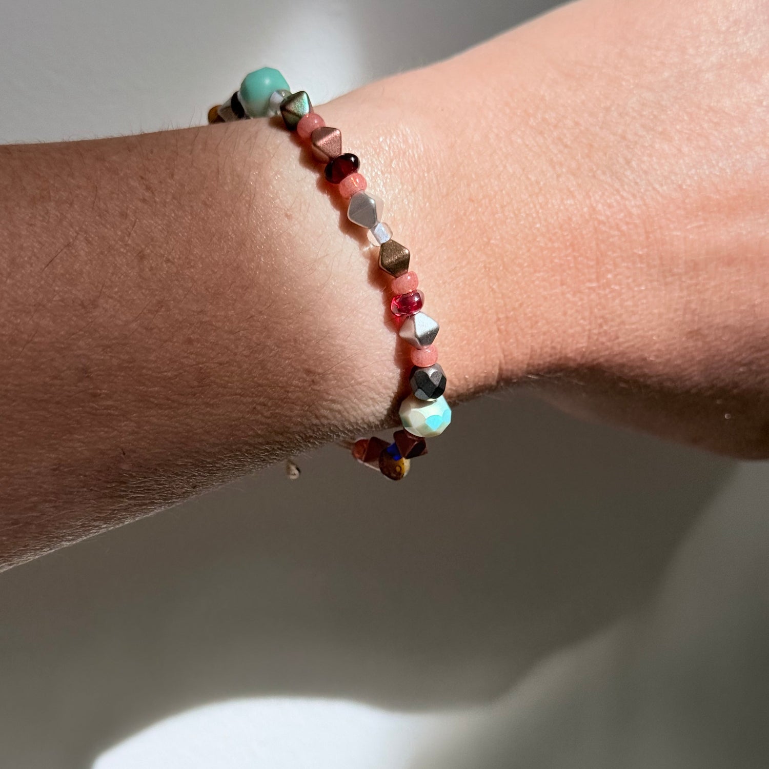 Close-up of a wrist wearing a beaded bracelet with a neutral background