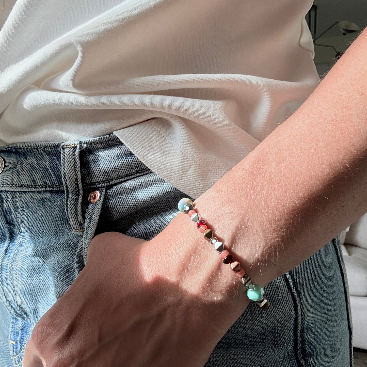 Person wearing a bracelet with colorful beads, sitting on a couch.