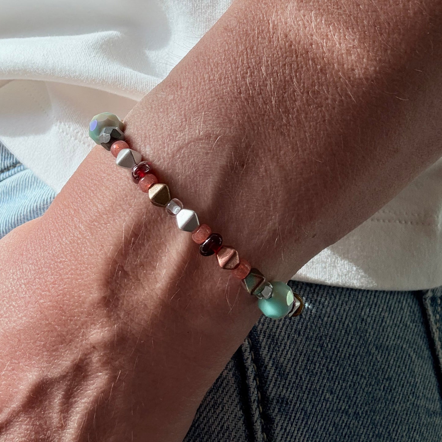 Close-up of a wrist wearing a beaded bracelet with a neutral background