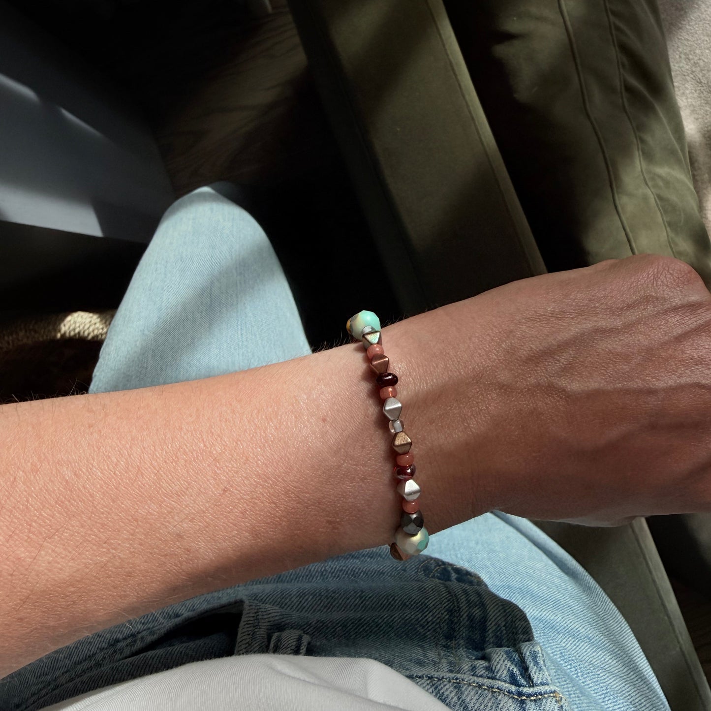 Close-up of a person's wrist wearing a beaded bracelet with a blurred background