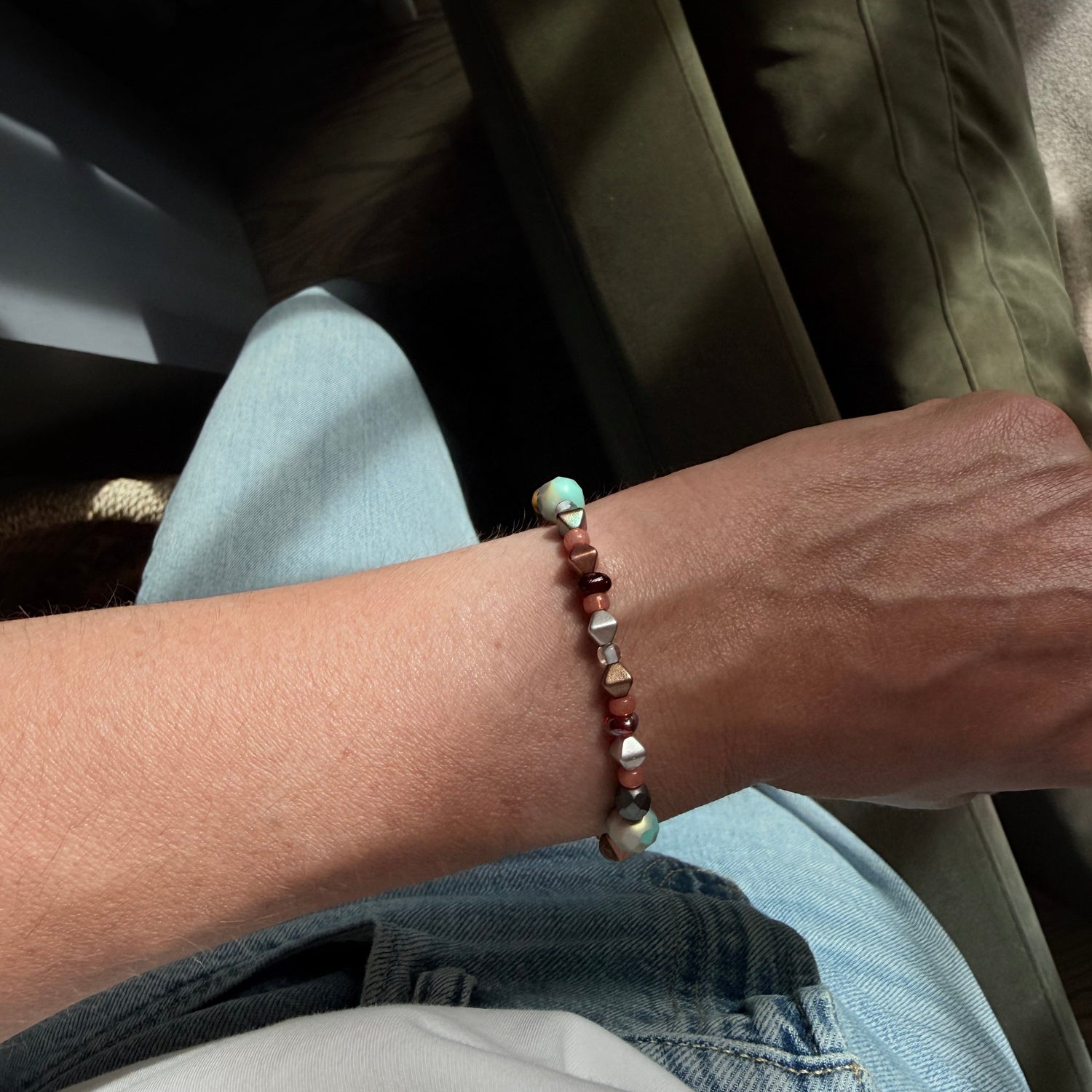 Close-up of a person's wrist wearing a beaded bracelet with a blurred background