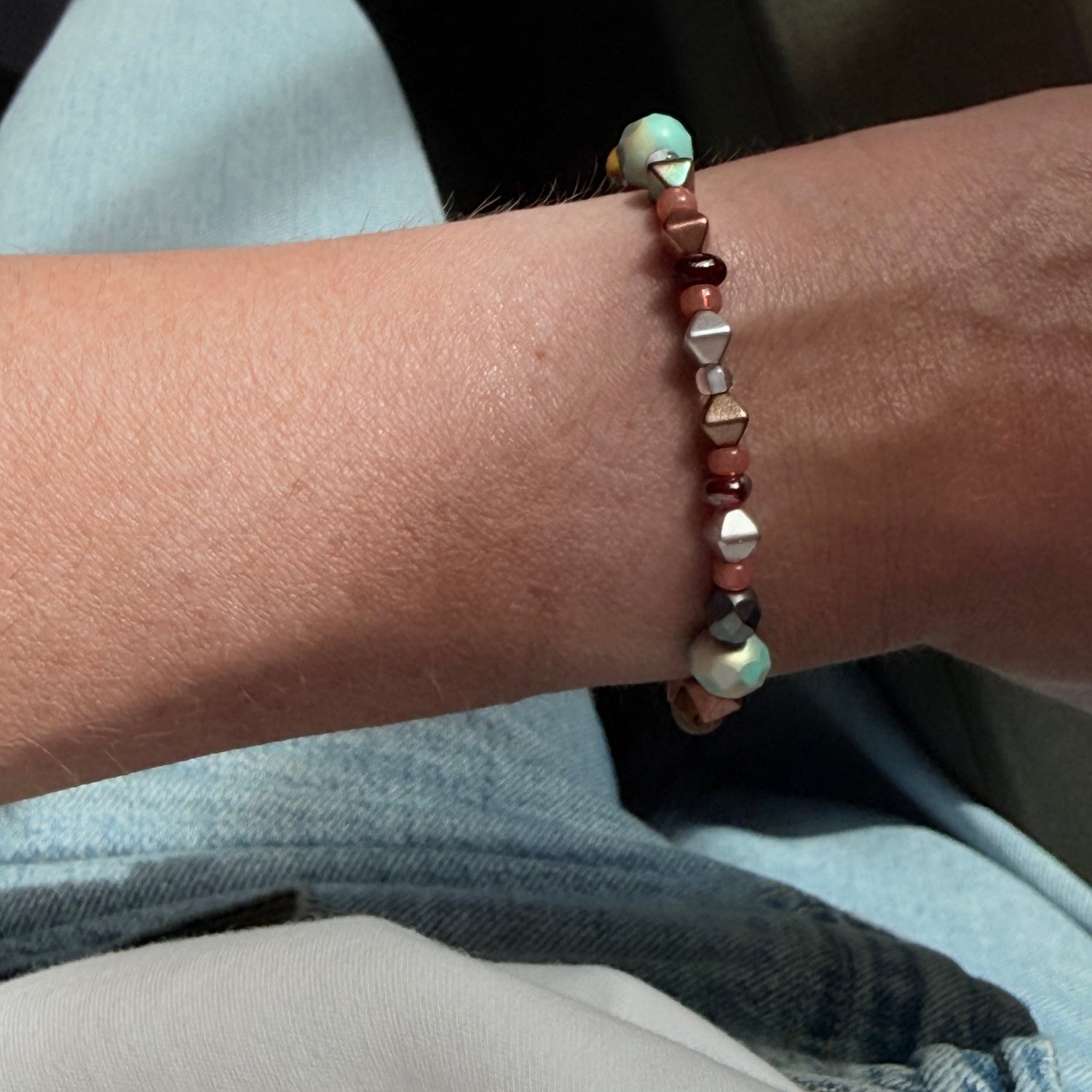 Close-up of a wrist wearing a beaded bracelet with a blurred background