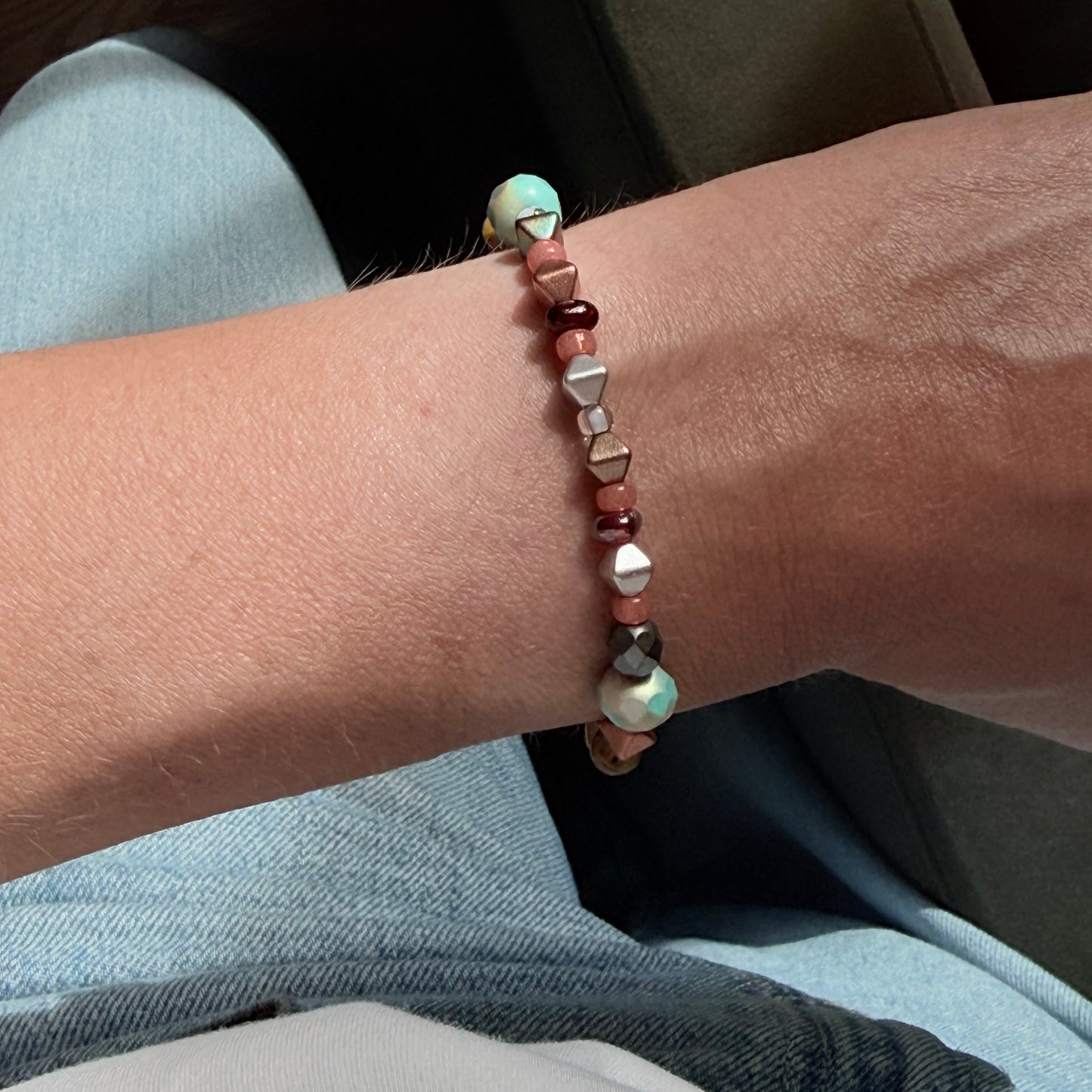 Close-up of a wrist wearing a beaded bracelet with a blurred background