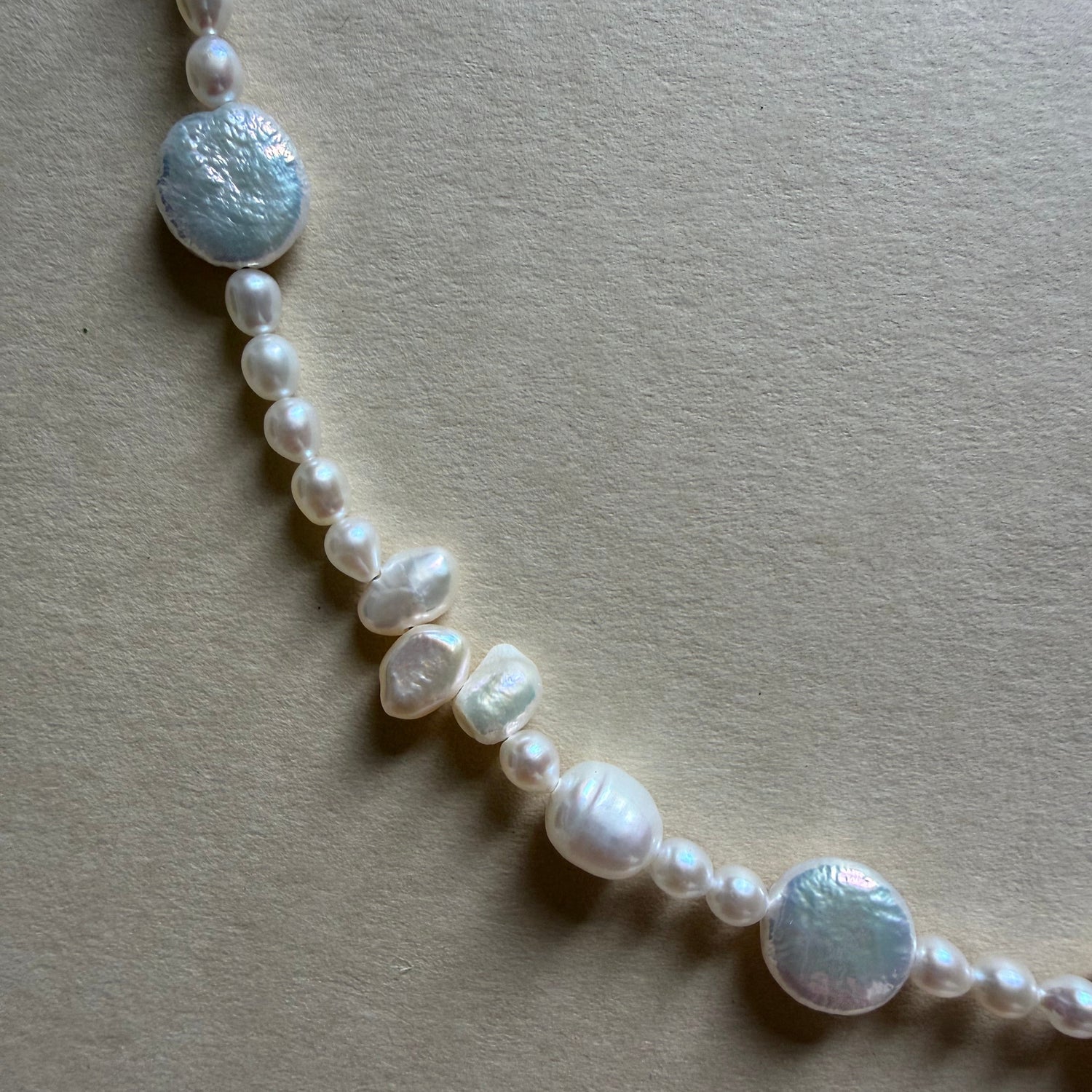 Pearl necklace with silver beads on a beige background