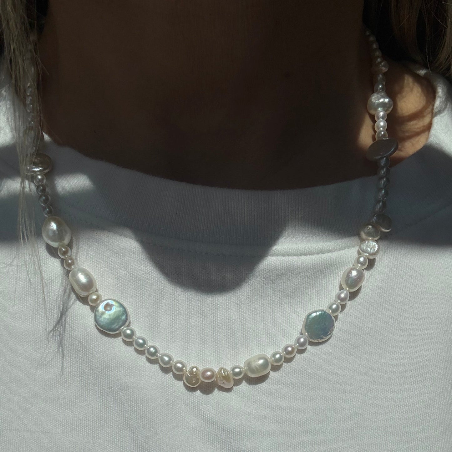 Pearl necklace with silver chain on a light fabric background