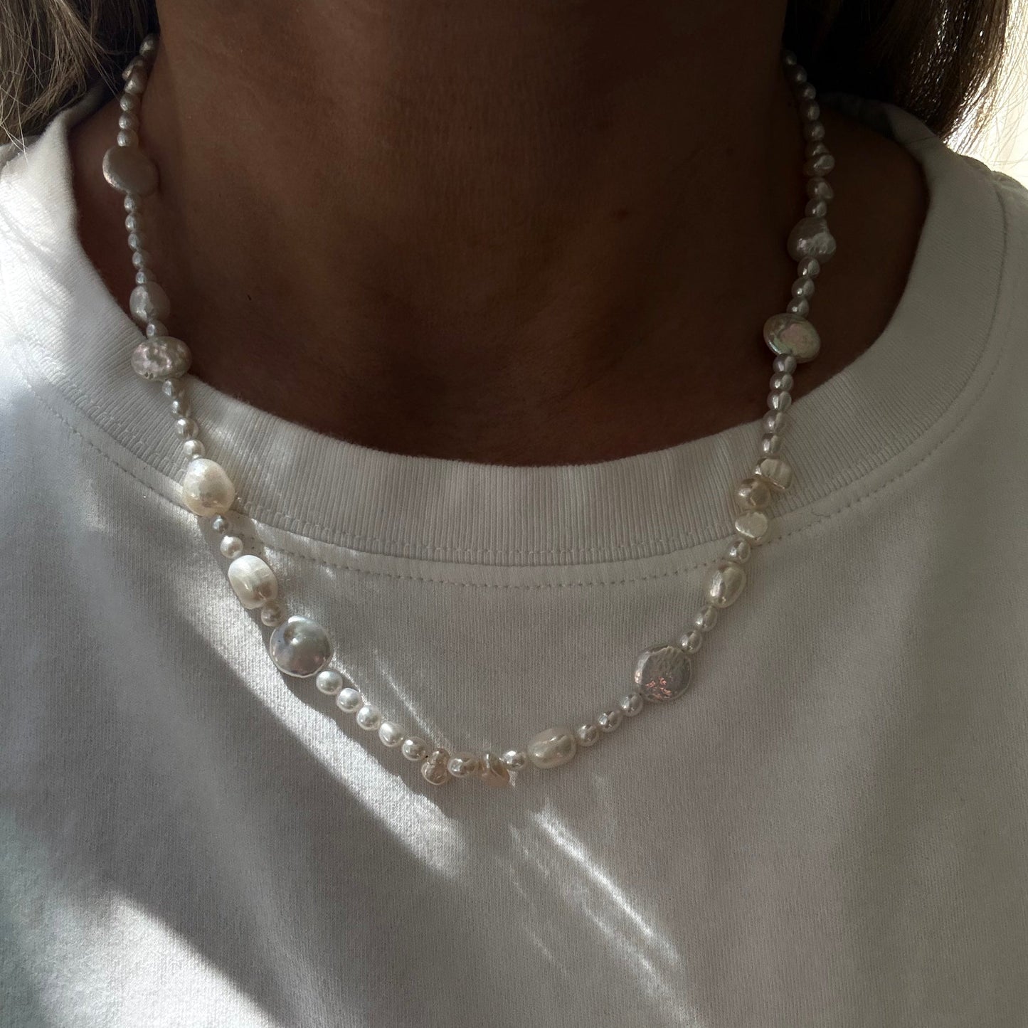 Close-up of a pearl necklace on a white shirt
