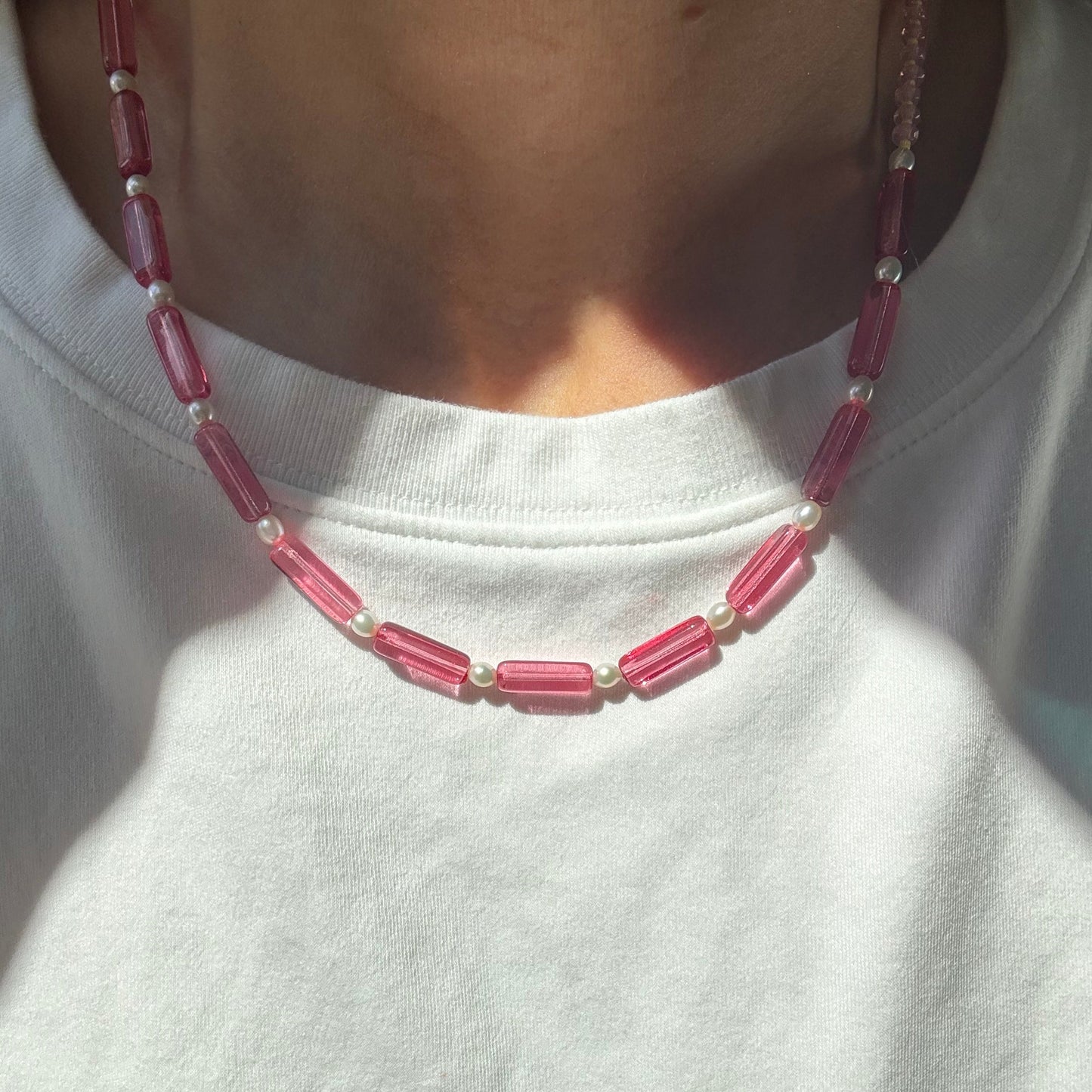 Close-up of a pink beaded necklace on a white shirt