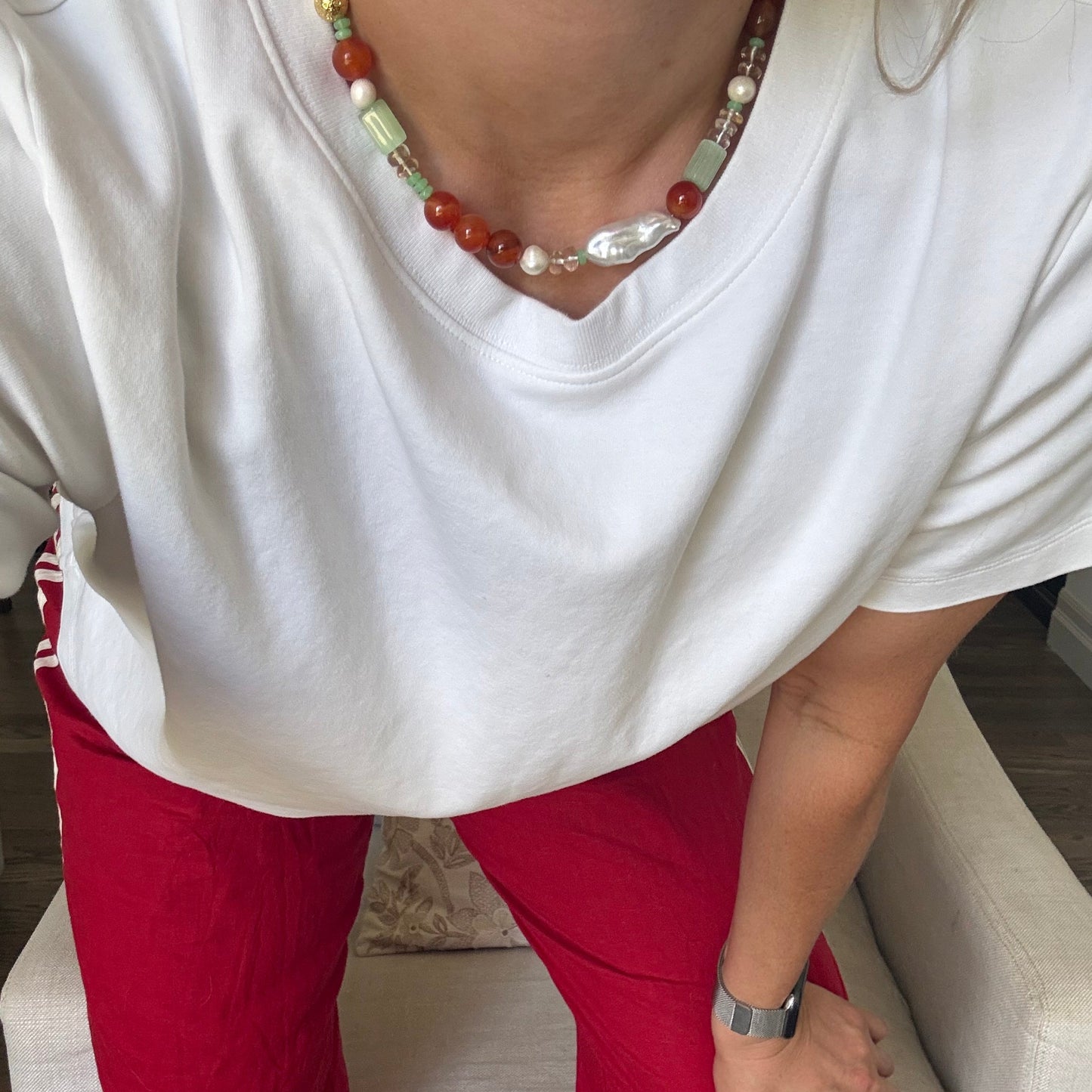 Person wearing a white garment with a red skirt, sitting on a white cushion.