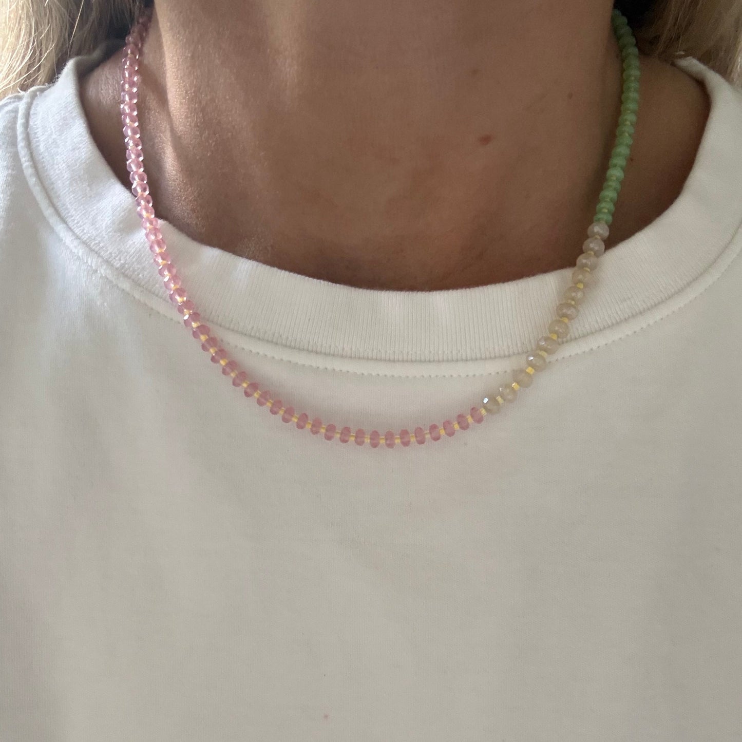 Close-up of a person wearing a white shirt with a beaded necklace.