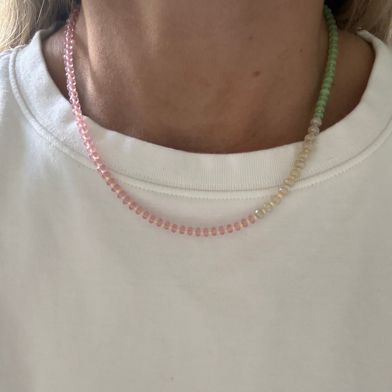 Close-up of a person wearing a white shirt with a beaded necklace.