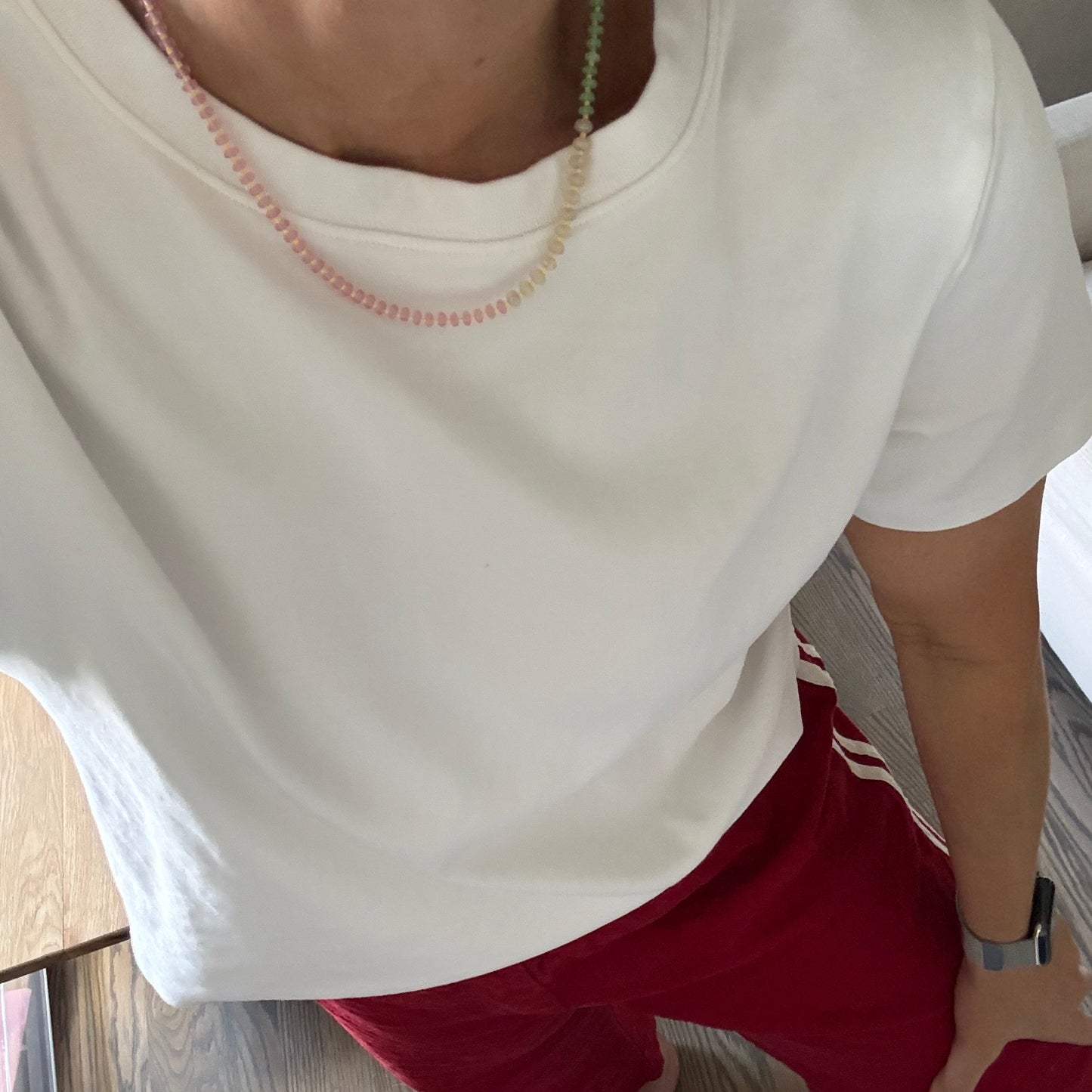 Person wearing a white tank top and red pants on a wooden floor.