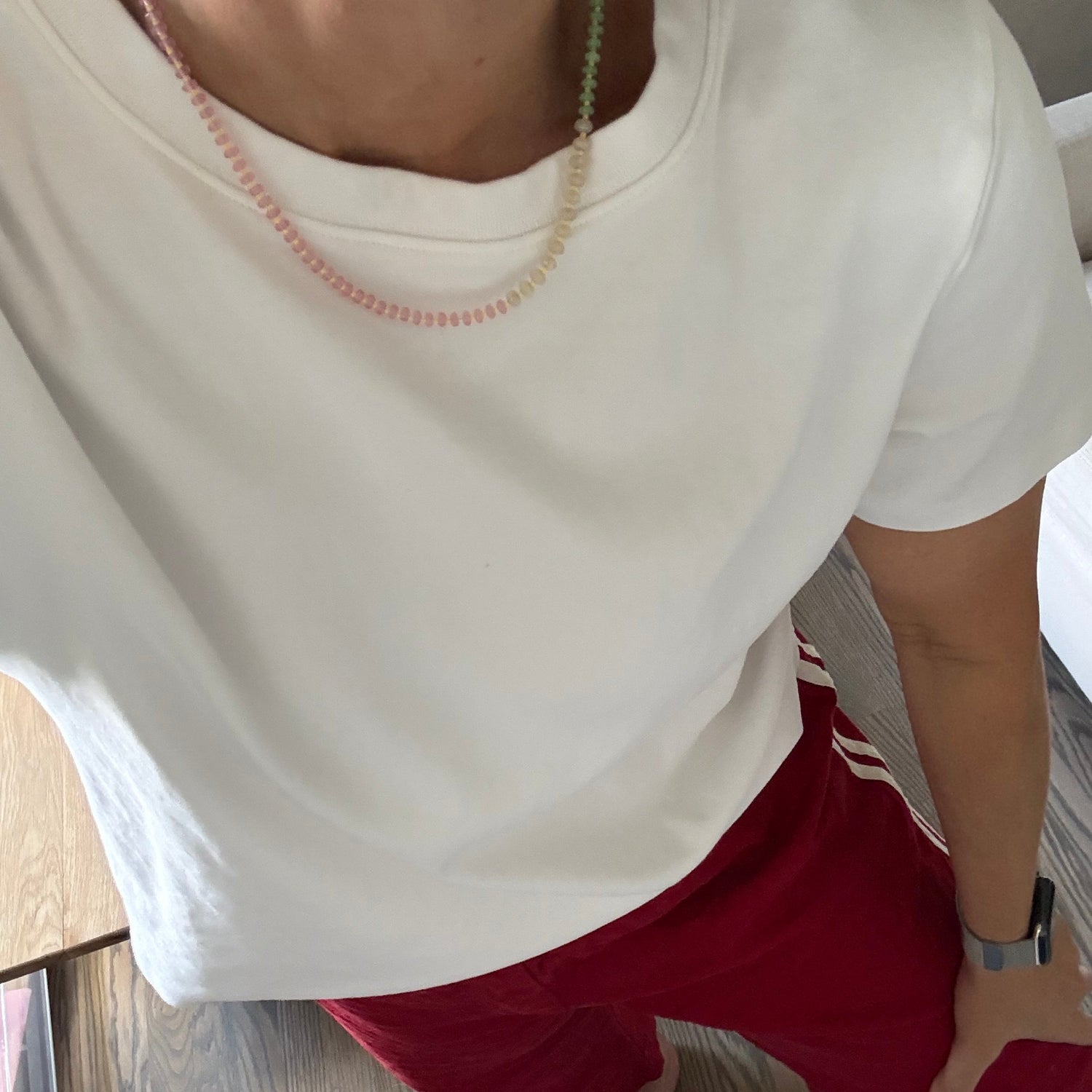 Person wearing a white tank top and red pants on a wooden floor.