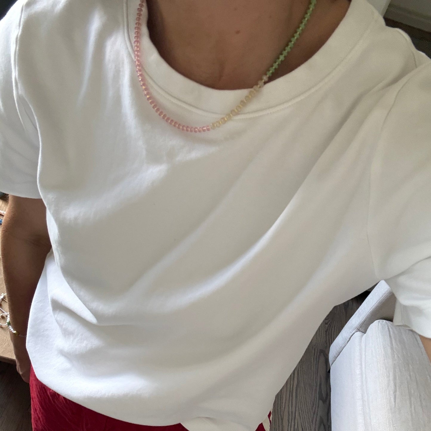 Person wearing a white top and red pants sitting on a couch.