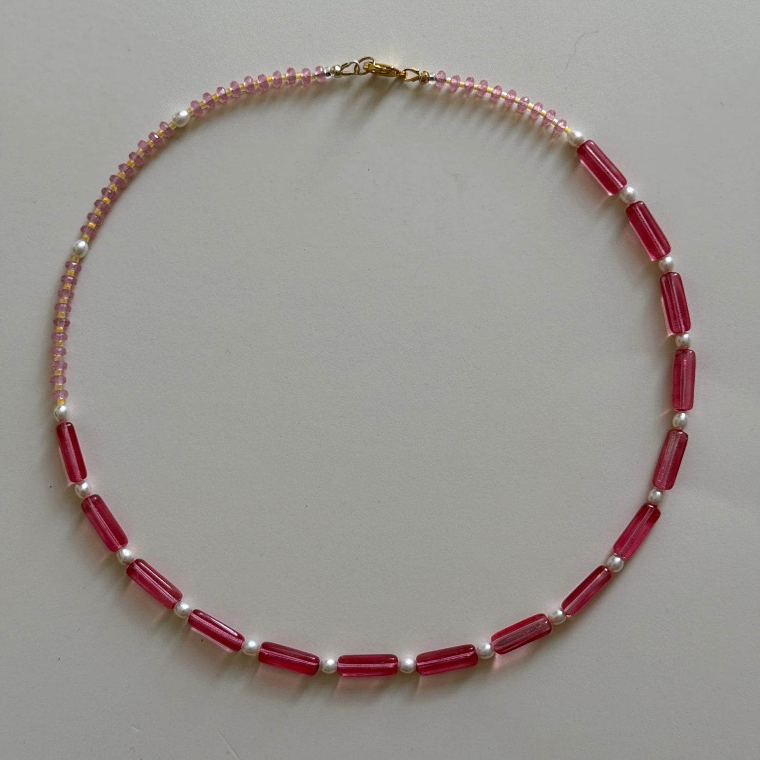 Beaded necklace with red and pink beads on a gray background