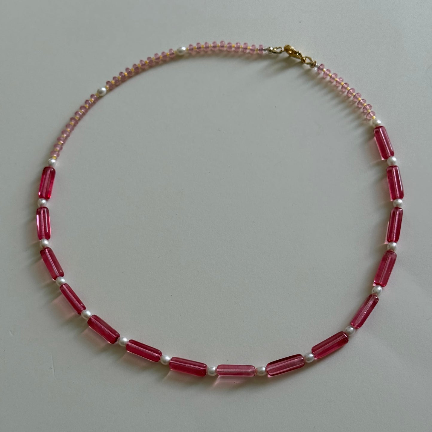 Necklace with red and white beads on a light gray background