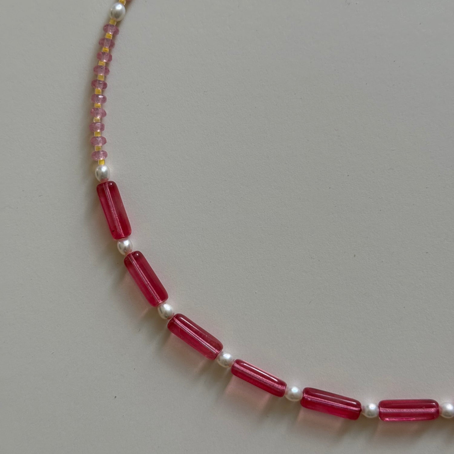 Necklace with red beads and pearls on a light gray background