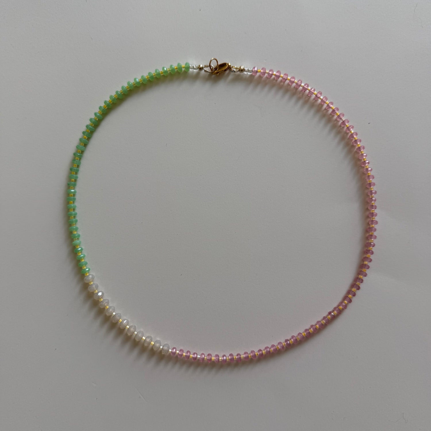 Beaded necklace with pink and green beads on a white background