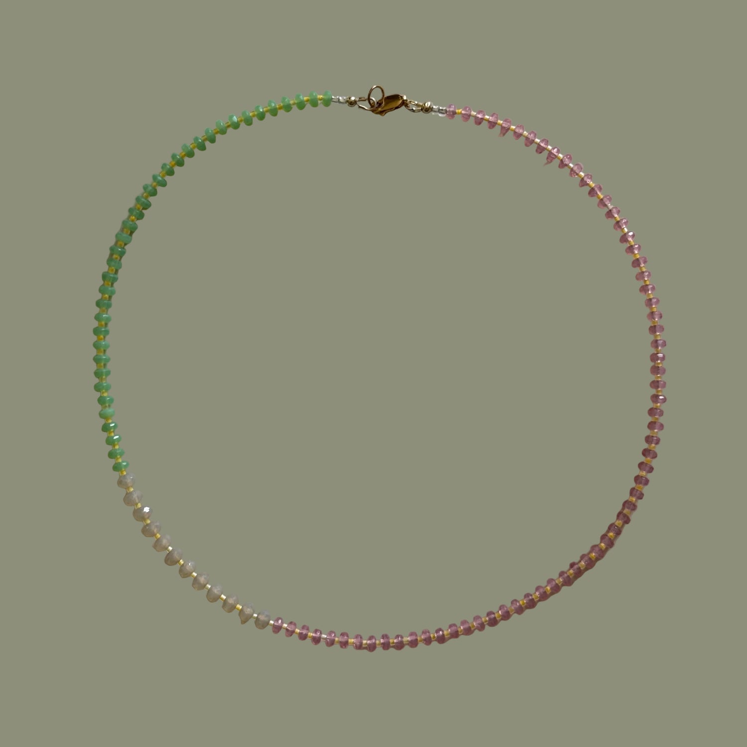 Beaded necklace with pink and green beads on a light gray background
