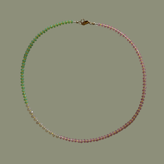 Beaded necklace with pink and green beads on a light gray background