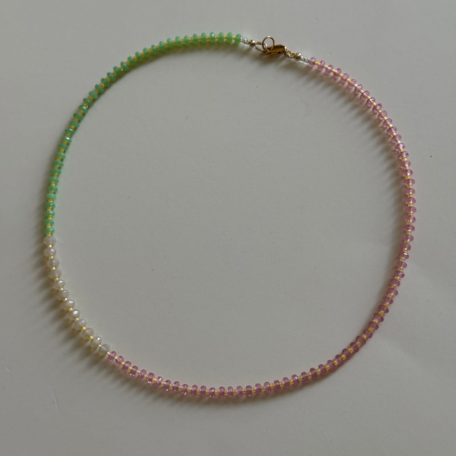 Necklace with pink and green beads on a light gray background