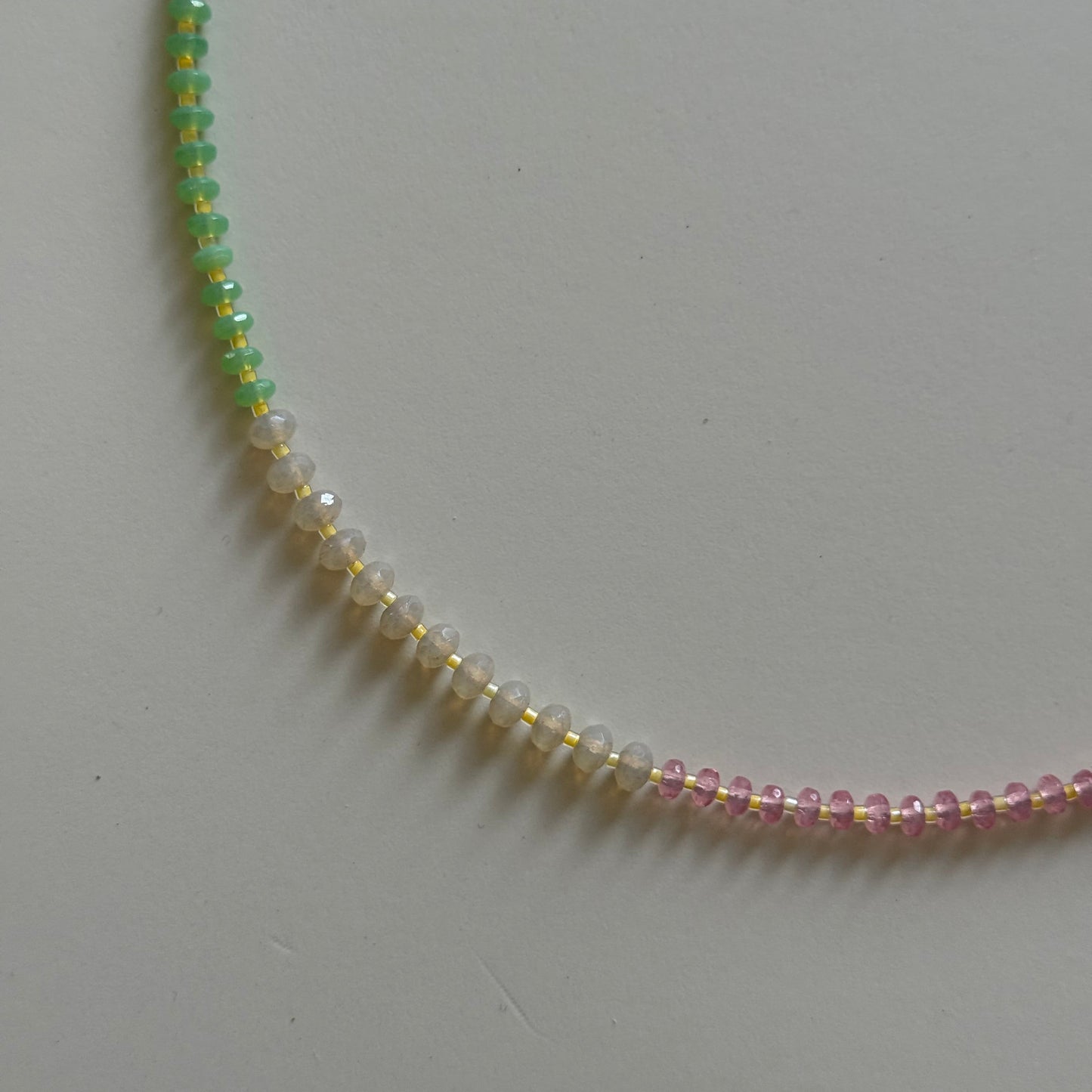 Close-up of a beaded necklace with multicolored beads on a light gray background