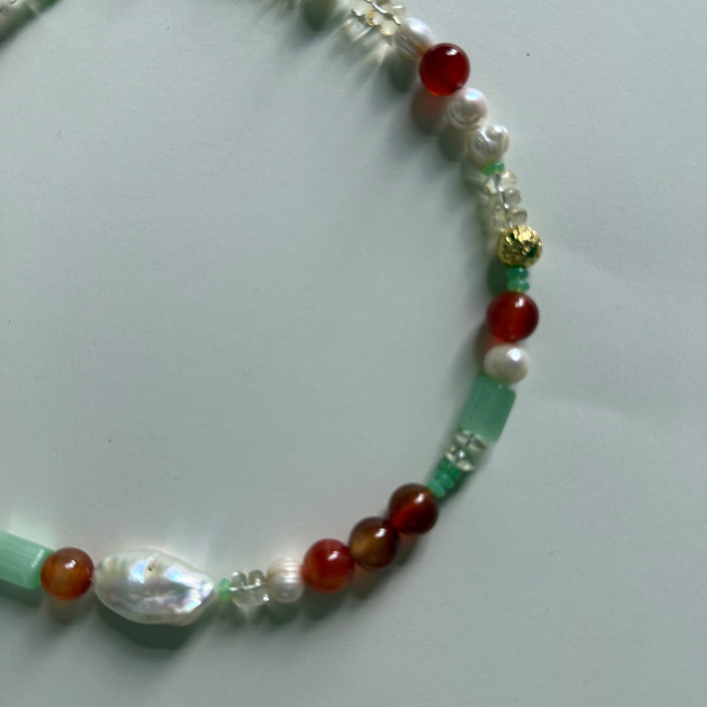 Beaded necklace with various colored beads on a light gray background