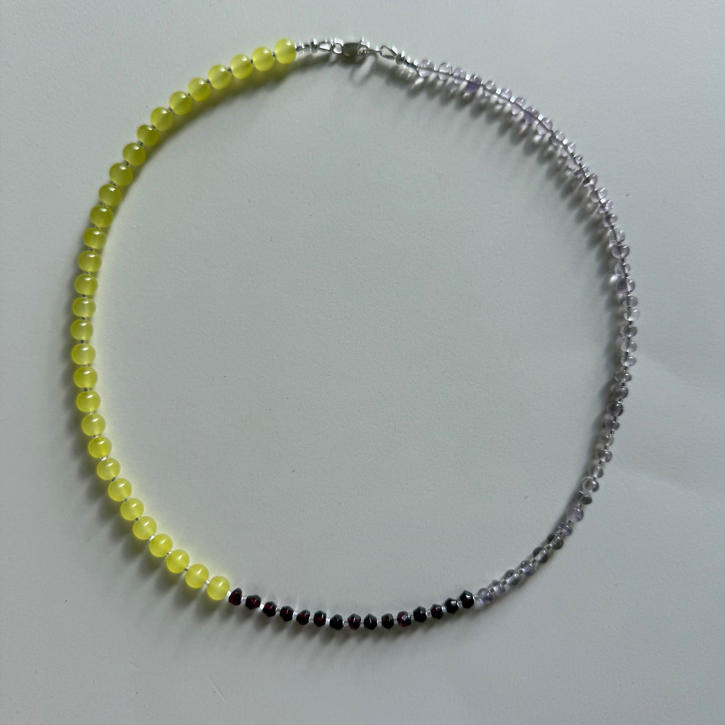 Necklace with yellow beads and a silver chain on a light gray background