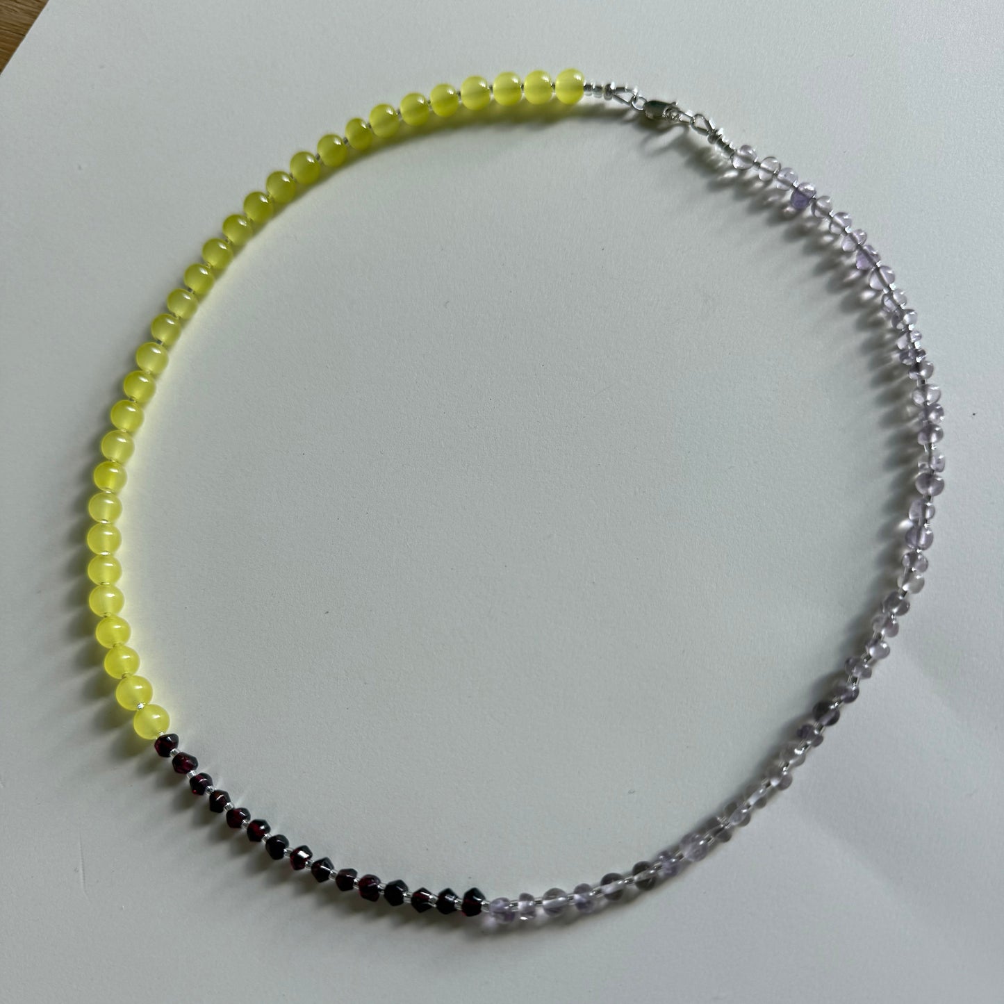 Beaded necklace with yellow, black, and clear beads on a white background