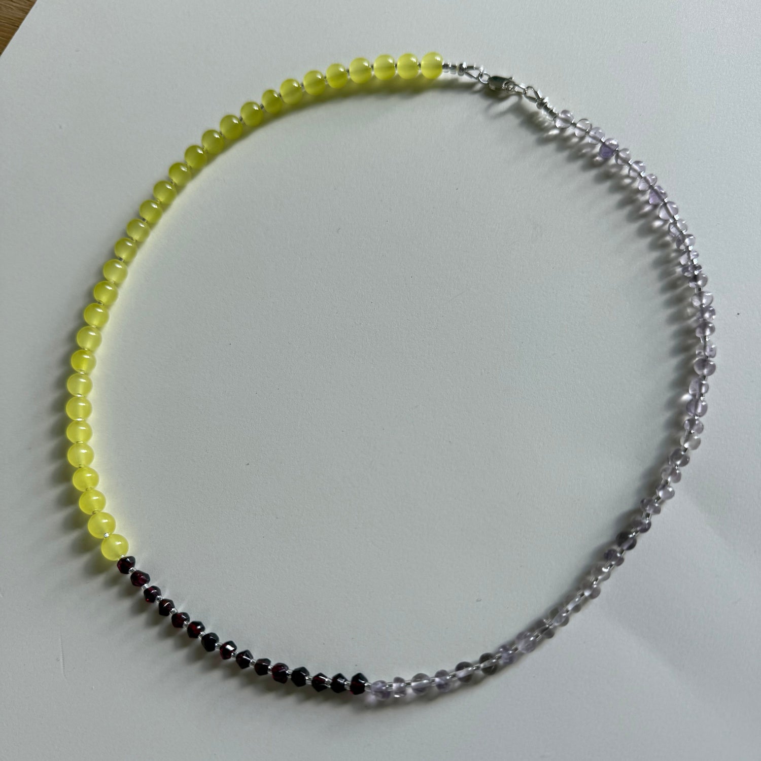 Beaded necklace with yellow, black, and clear beads on a white background