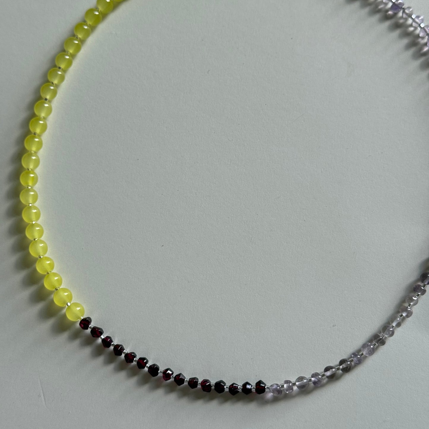 Necklace with yellow beads and a silver chain on a light gray background