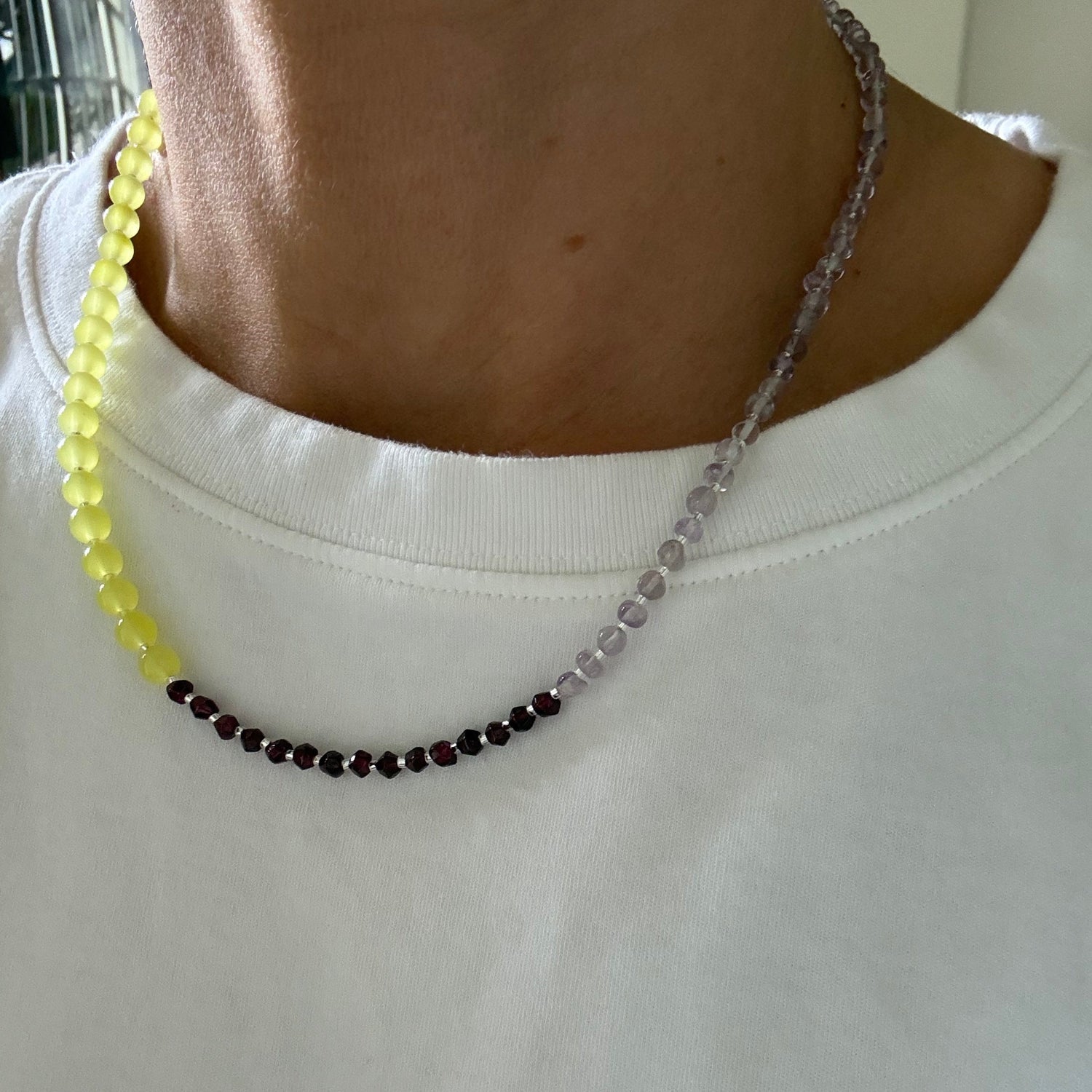 Close-up of a beaded necklace with a white garment in the background