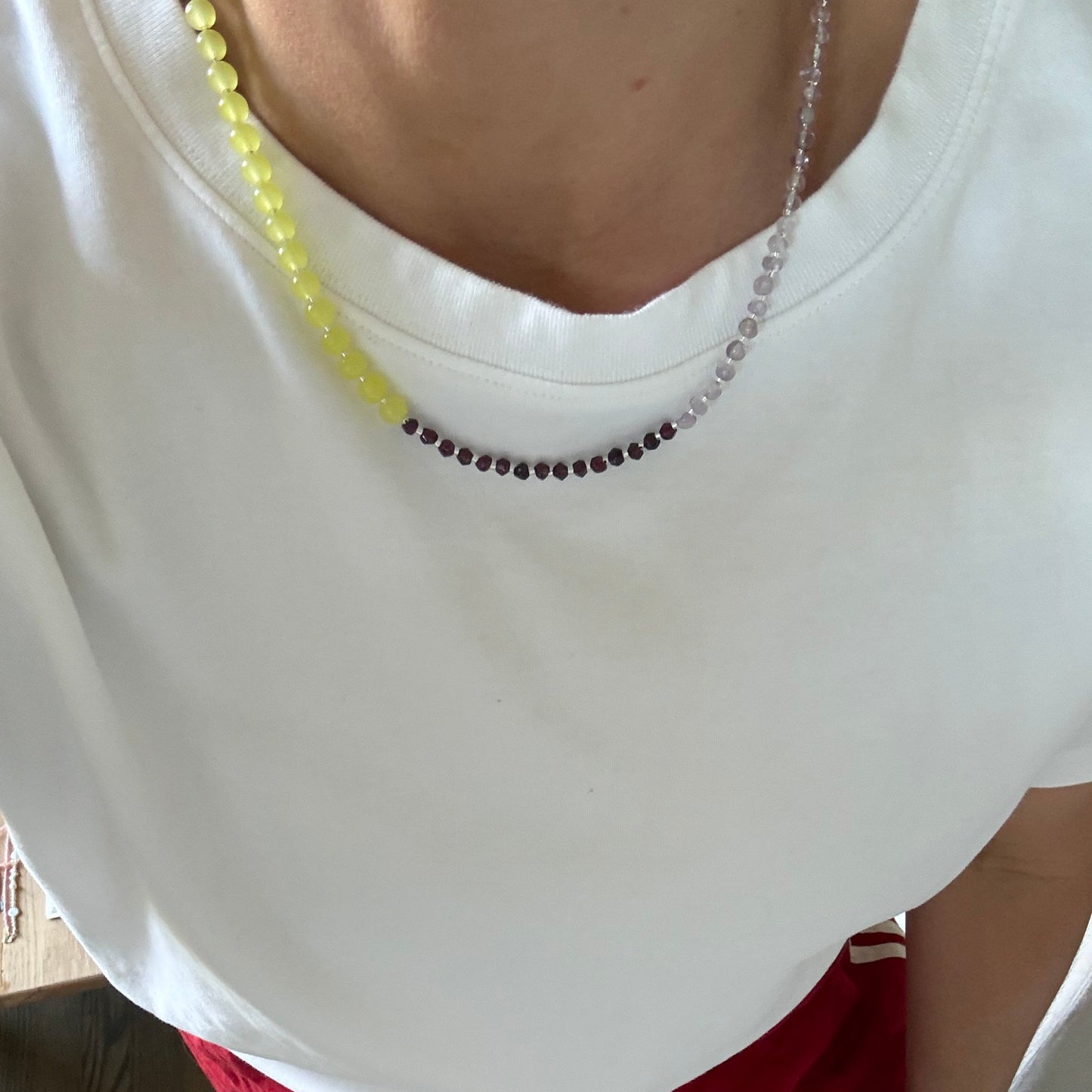 Person wearing a white top with a decorative neckline and red pants sitting on the floor.