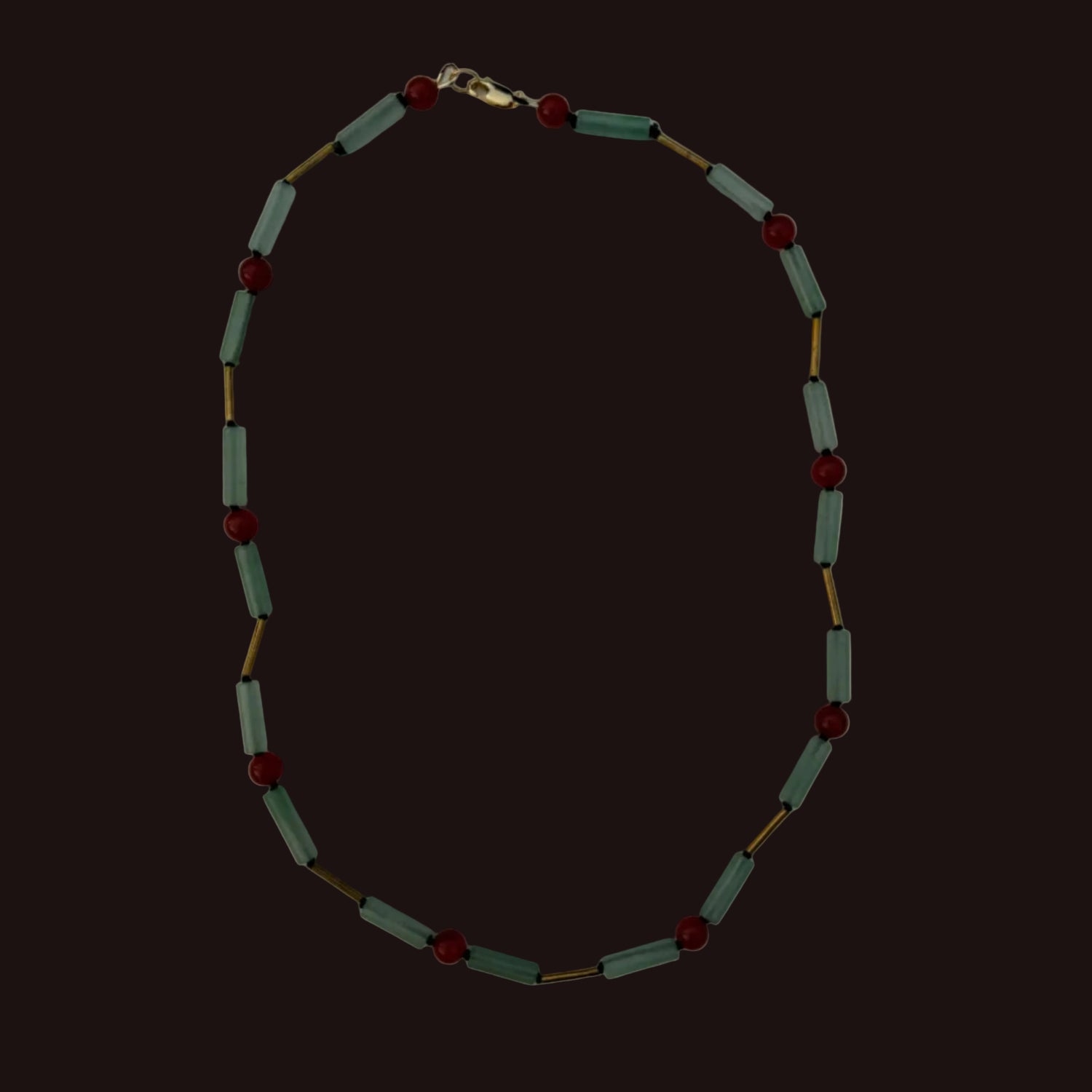 A beaded necklace featuring light sage green cylindrical beads and small dark red round beads, separated by thin gold-tone metal links, displayed on a plain light gray background.