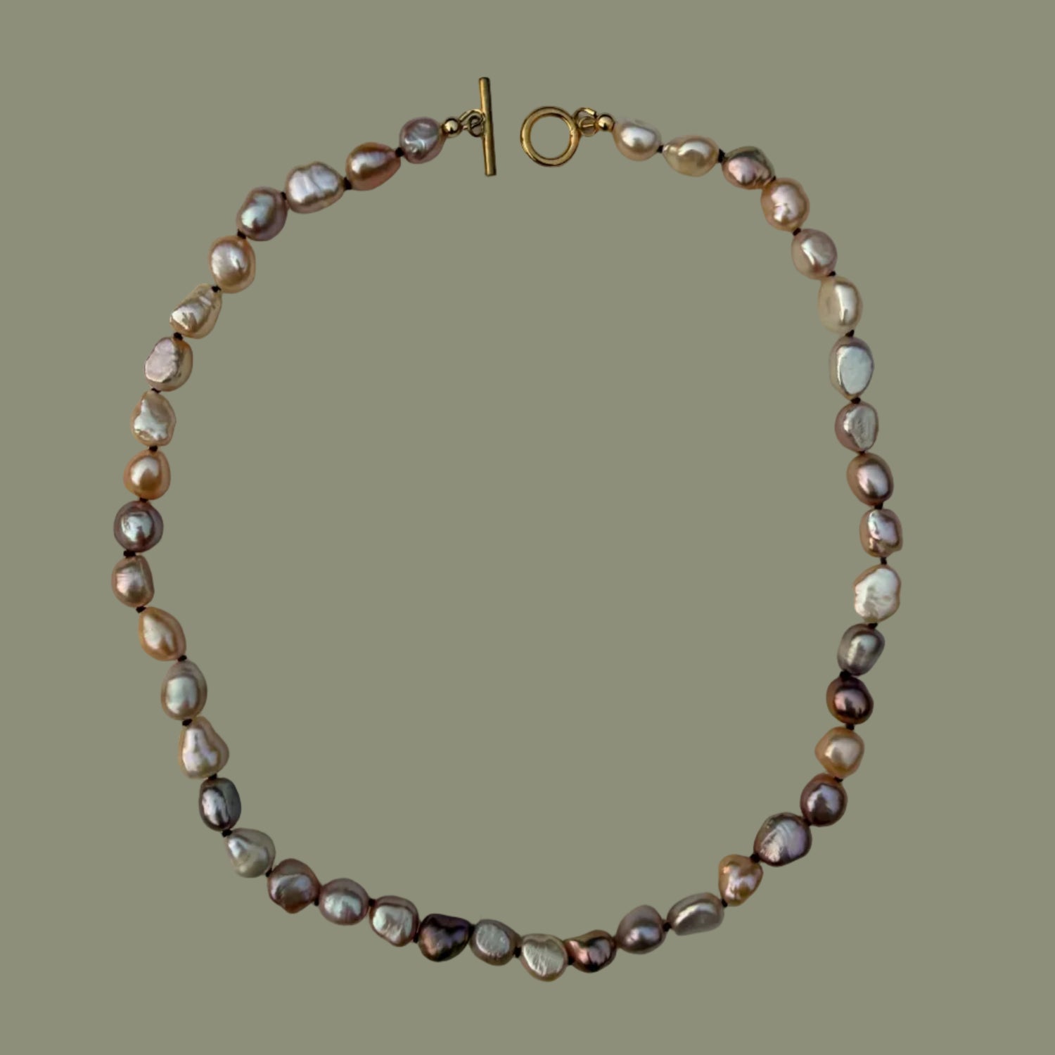 A baroque pearl necklace with a gold clasp, displayed on a solid olive green background.