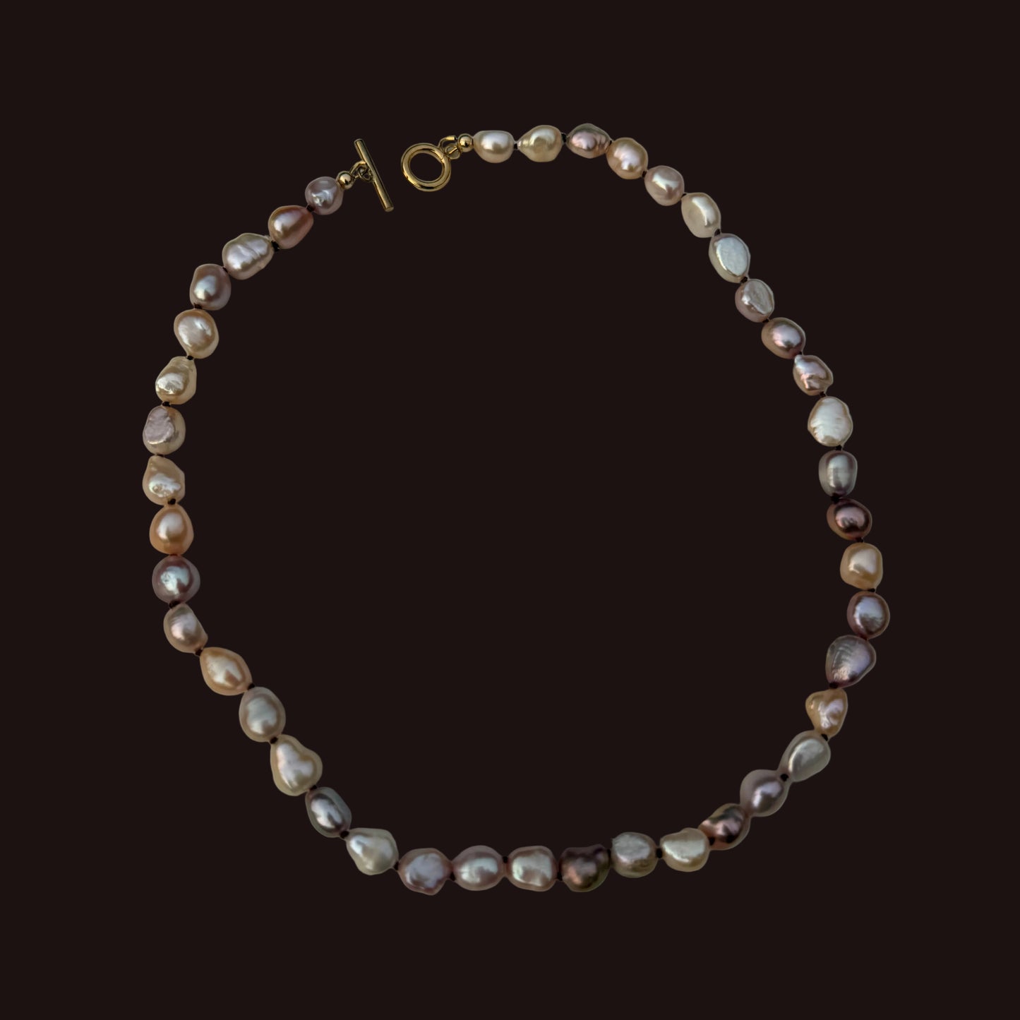 A baroque pearl necklace with a gold toggle clasp, displayed on a light gray background.