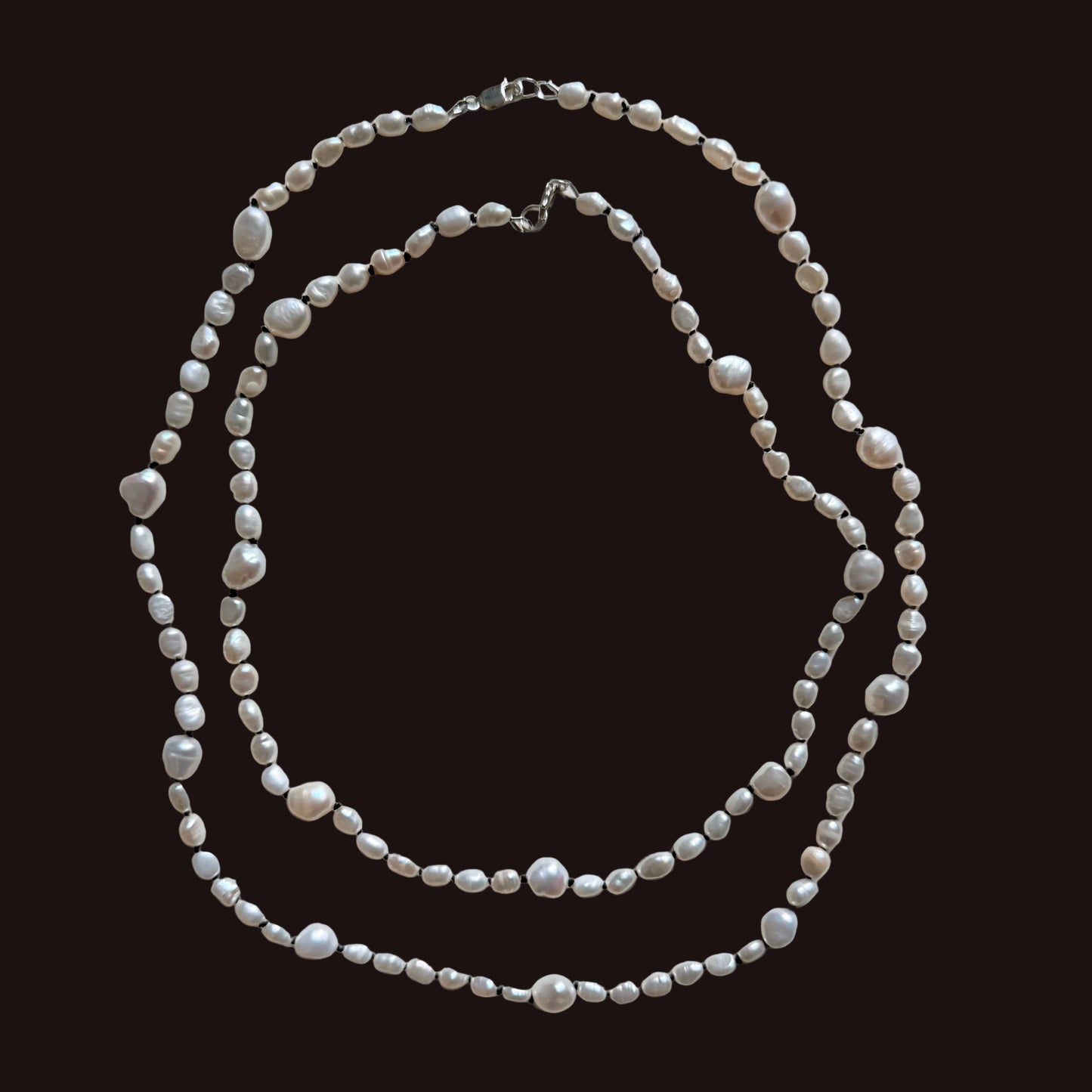 A double-strand necklace made of irregular white freshwater pearls and small silver-toned beads, laid flat on a light gray background. A measurement label is visible along the bottom edge of the photo.