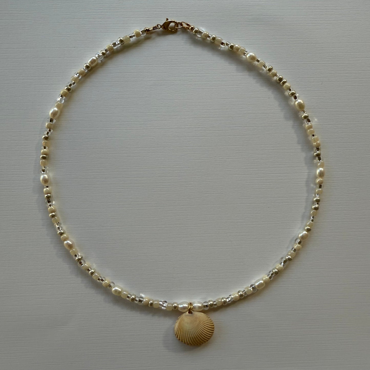 Necklace with shell pendant on a light gray background