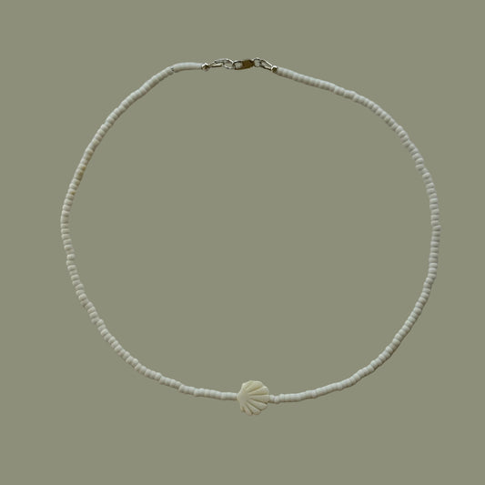Pearl necklace with a shell charm on a light gray background